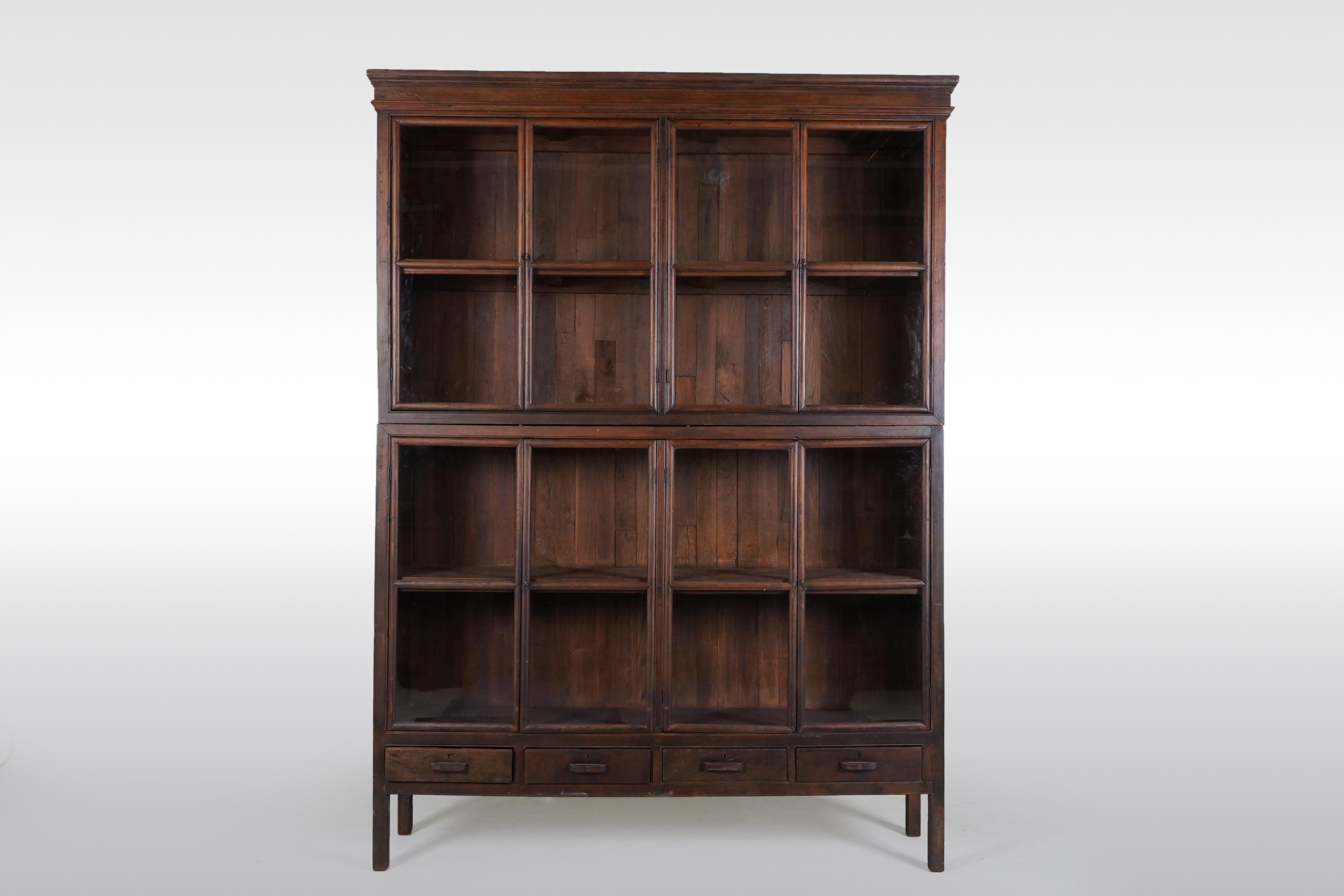 This large antique book cabinet was made from solid teak wood and dates to the early 1900's. During the British Empire in India and Burma much furniture was made in the Anglo-Indian style using native hardwoods and native craftsmen. Styles closely