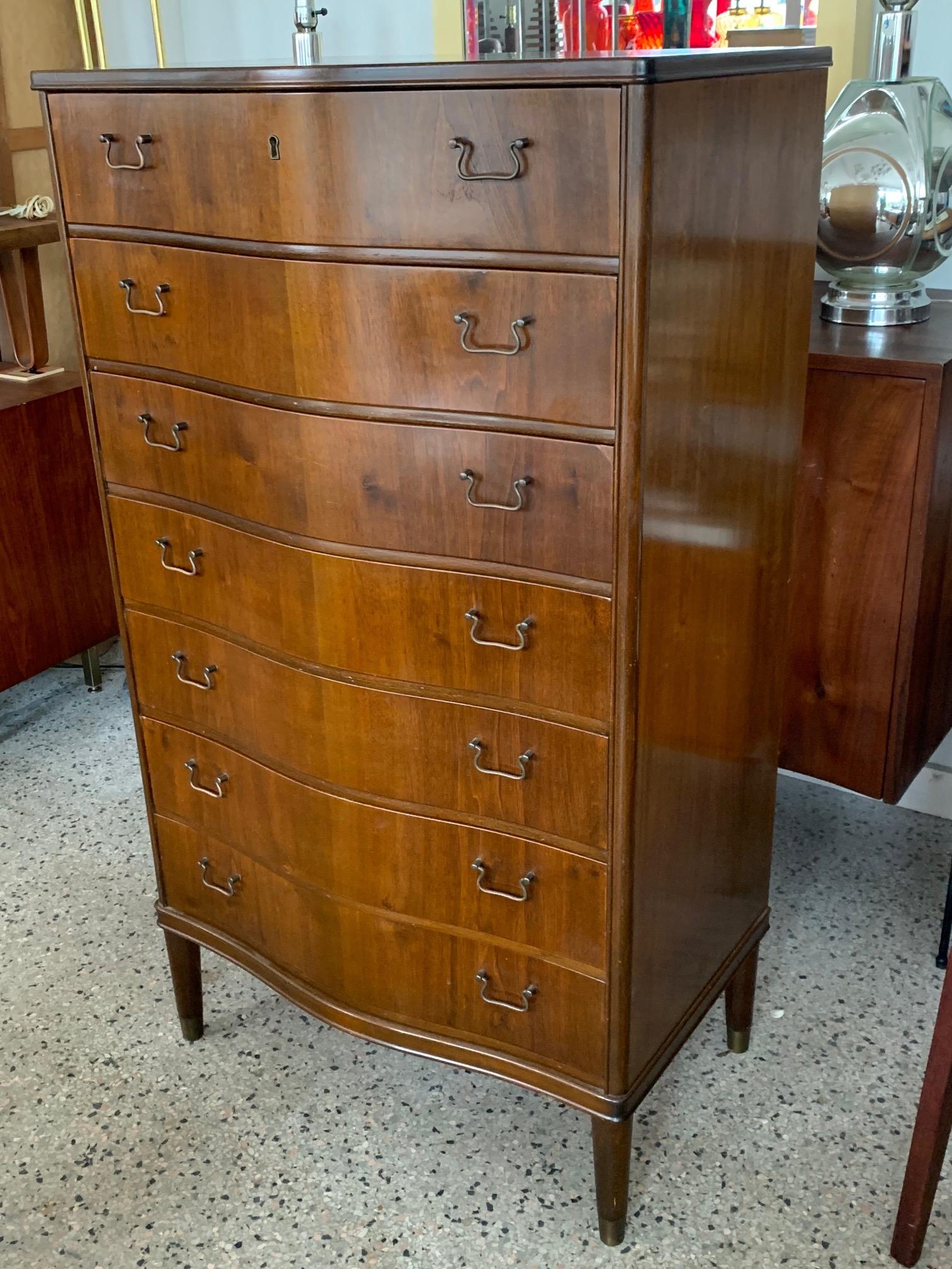 An unusual, seven drawers, tall Danish chest with bowed front. Elegant brass hardware, brass sabots.