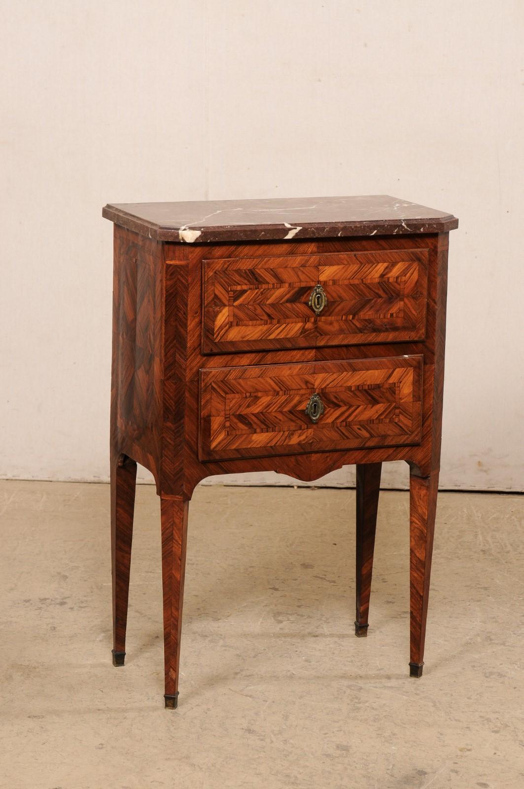 An Italian tall comodino, with original marble top and gorgeous veneer & inlays, from the 19th century. This antique side chest from Italy features its original marble top with canted front corners, atop a case two drawer case adorn with great inlay