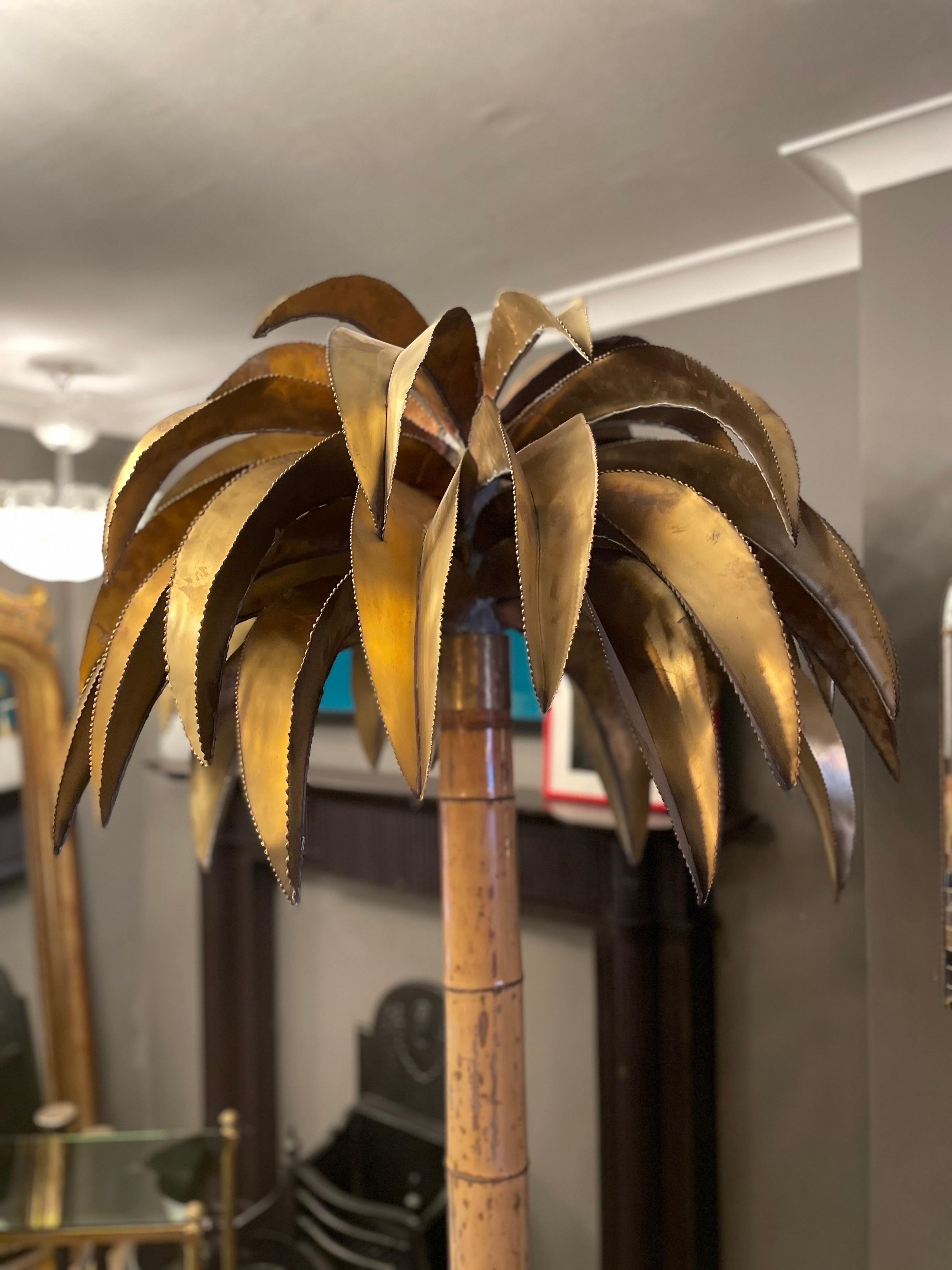 A very tall and rarer model of the Jansen Palm tree. The bamboo stem as opposed to the brass. A large and wide brass palm tree canopy with the bamboo stem supported in and brass and black lacquered base with hidden wheels beneath for movement. An