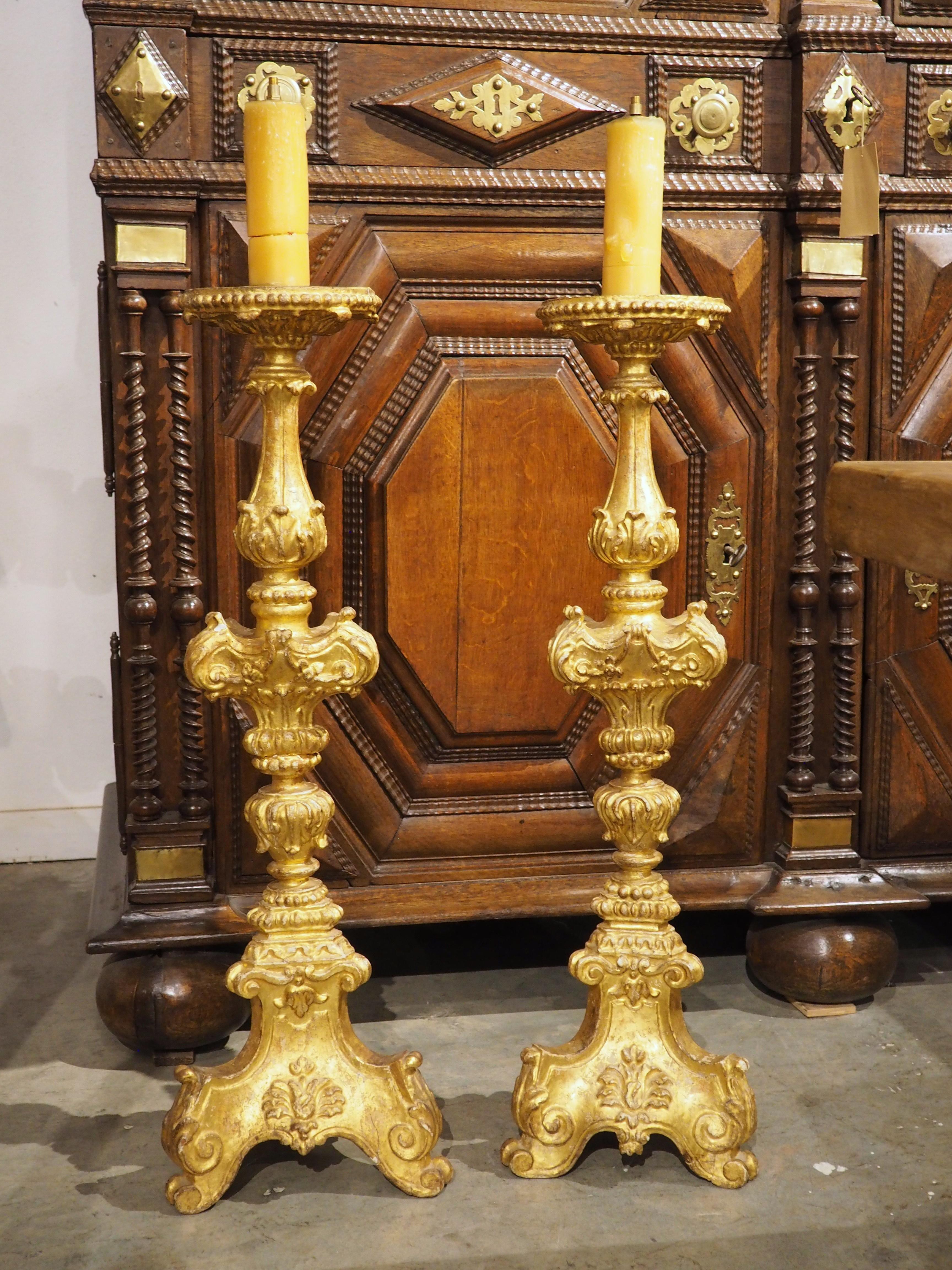 More information coming soon…

Dating to the 1700s, this pair of French giltwood candlesticks are a towering 45 inches tall.  The tripartite base consists of curled acanthus feet over tight volute whorls.  The undulating columns are adorned with a