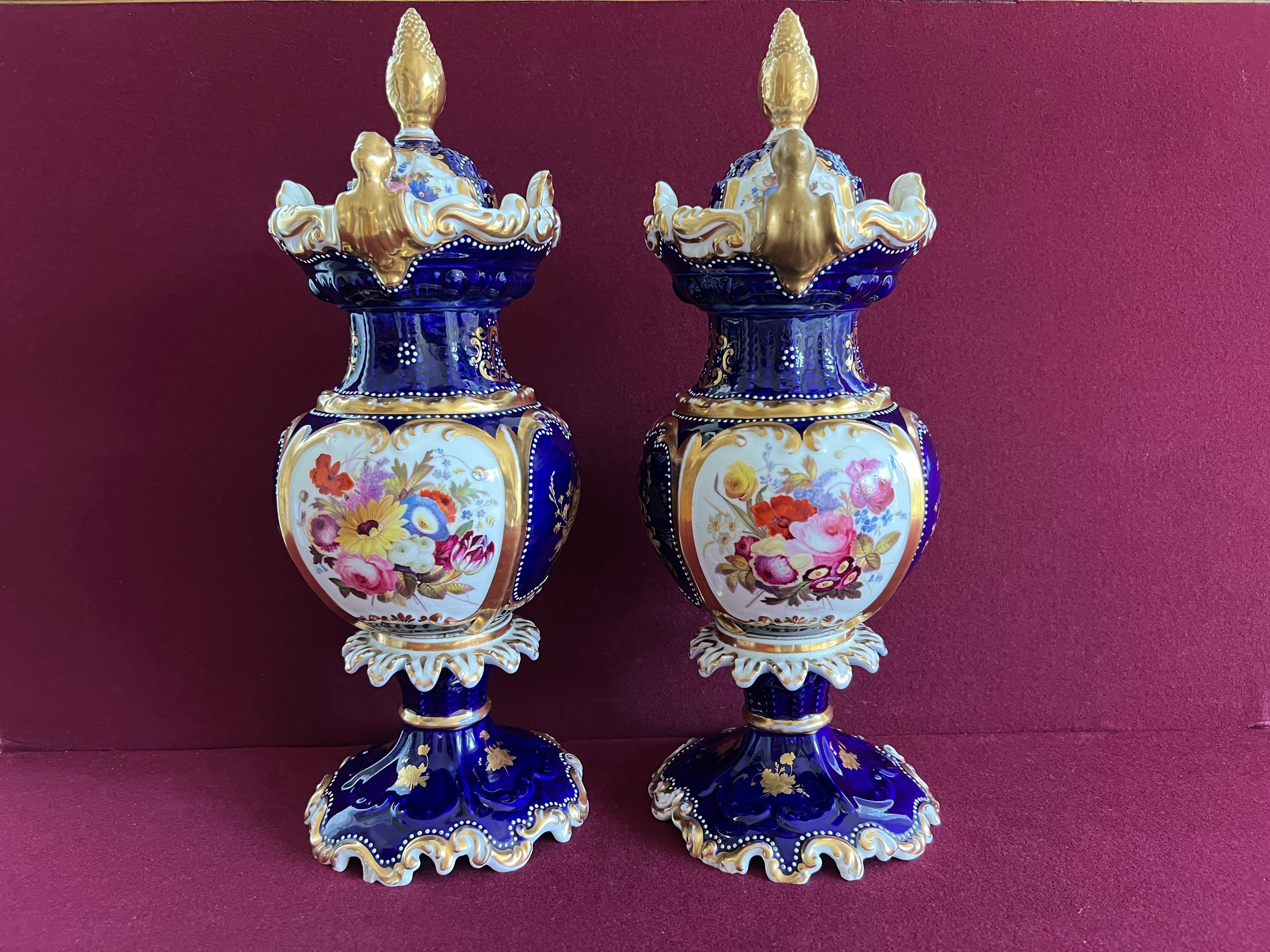 A tall pair of Chamberlain Worcester porcelain vases and covers, typical of the 1840's. Finely decorated with panels of summer flowers, chased gilding and 'fancy birds' in landscapes with an underglaze blue ground, richly gilded and decorated with