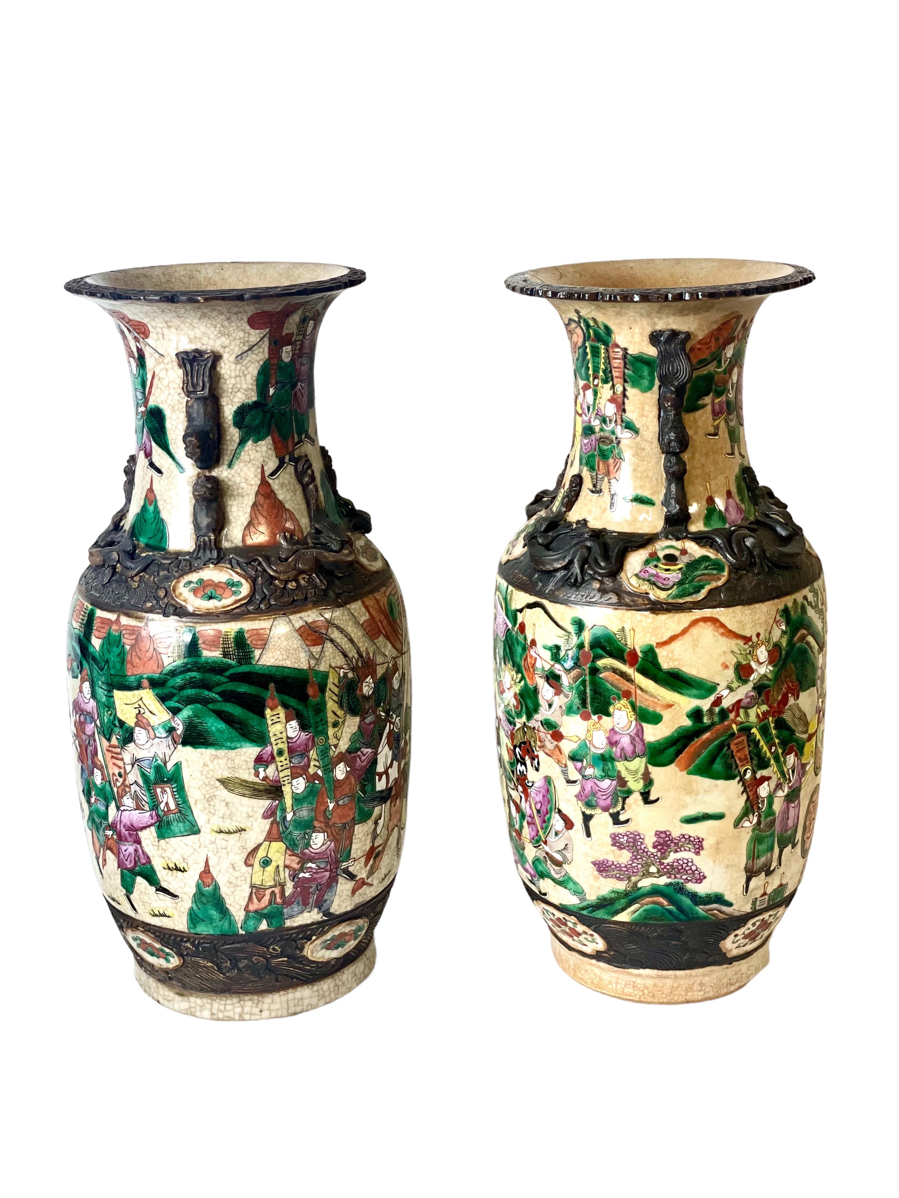 A pair of large ceramic Chinese crackle glaze baluster vases, commonly known as 'Nanjing' porcelain. Dating from the 19th century, these elegant polychrome enamelled vases are decorated on their lower half with traditional scenes of jousting, combat
