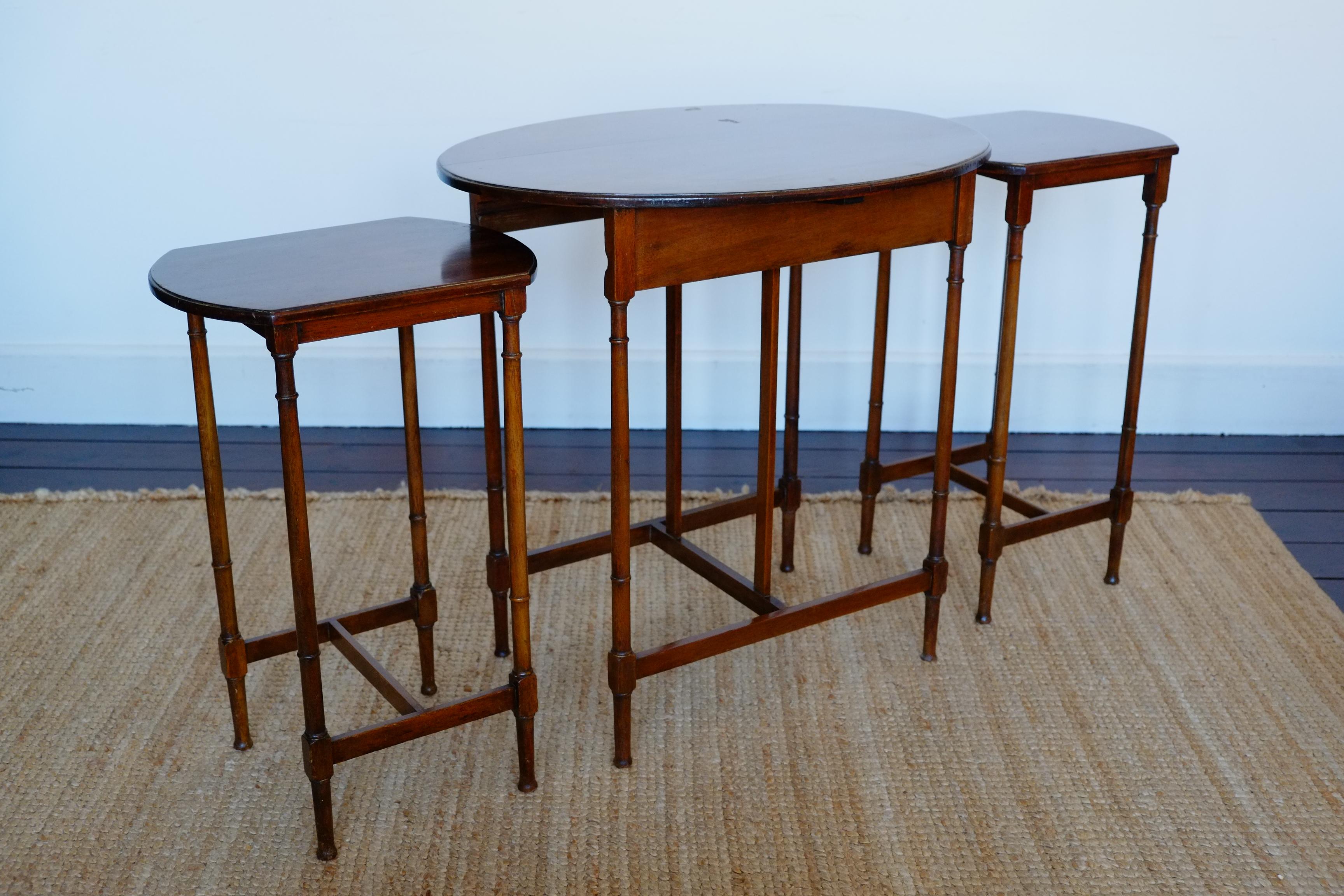 A beautiful and elegant mid-century set of three nesting tables. These solid mahogany nesting tables have a beautiful tall, slim design with oval shaped table tops. Standing on turned slim round legs with contrasting rectangular horizontal supports.