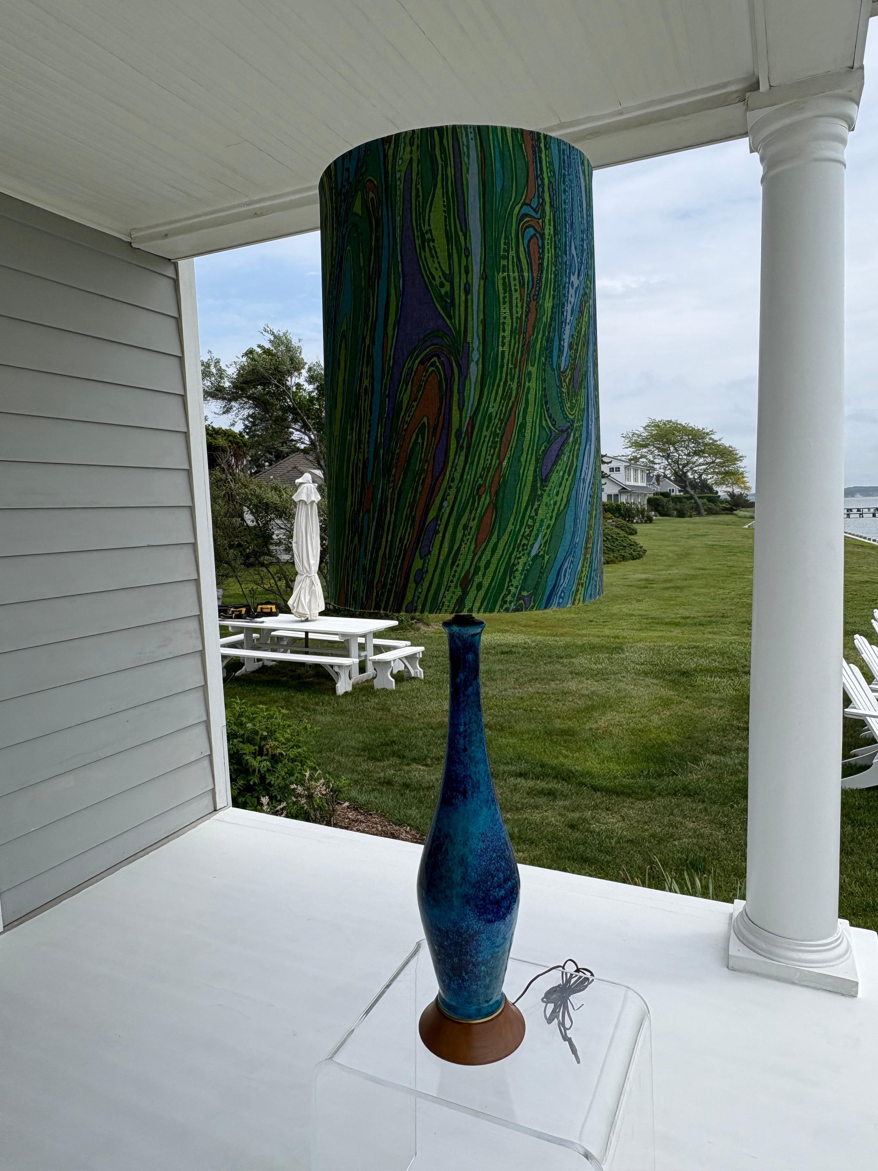 Beautiful tall marbleized blue ceramic table lamp with great curves . The base is solid walnut and the  elongated psychedelic drum shade has an incredible swirling pattern of blues , Pucci style . A great conversation piece ! You won’t see this
