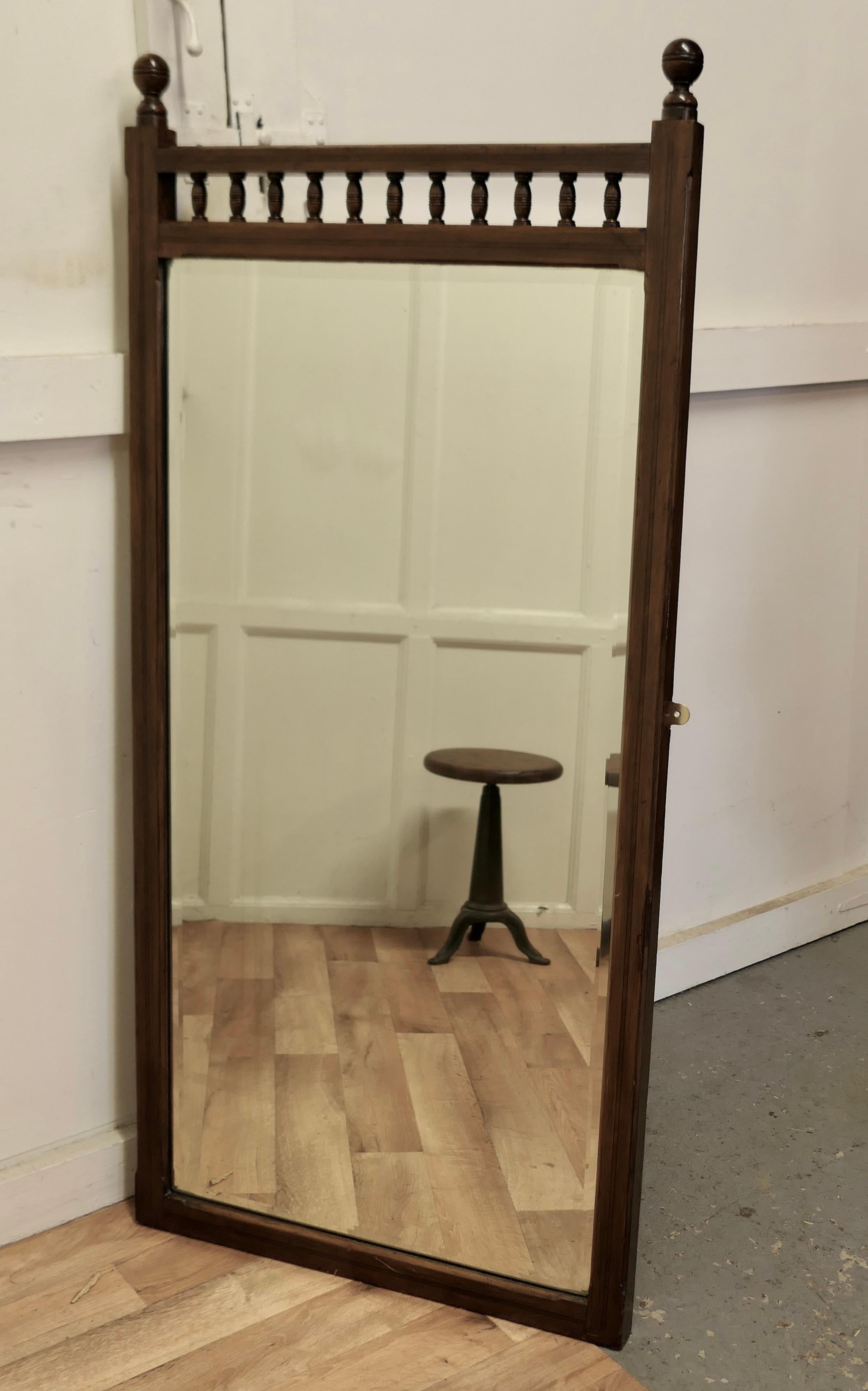 A Tall Walnut Arts and Crafts dressing mirror

This is a long Mirror the frame is in figured walnut with a little inlaid decoration at the sides, a row of turned spindles and curved knobs on the top
Both the frame and the bevelled mirror are in