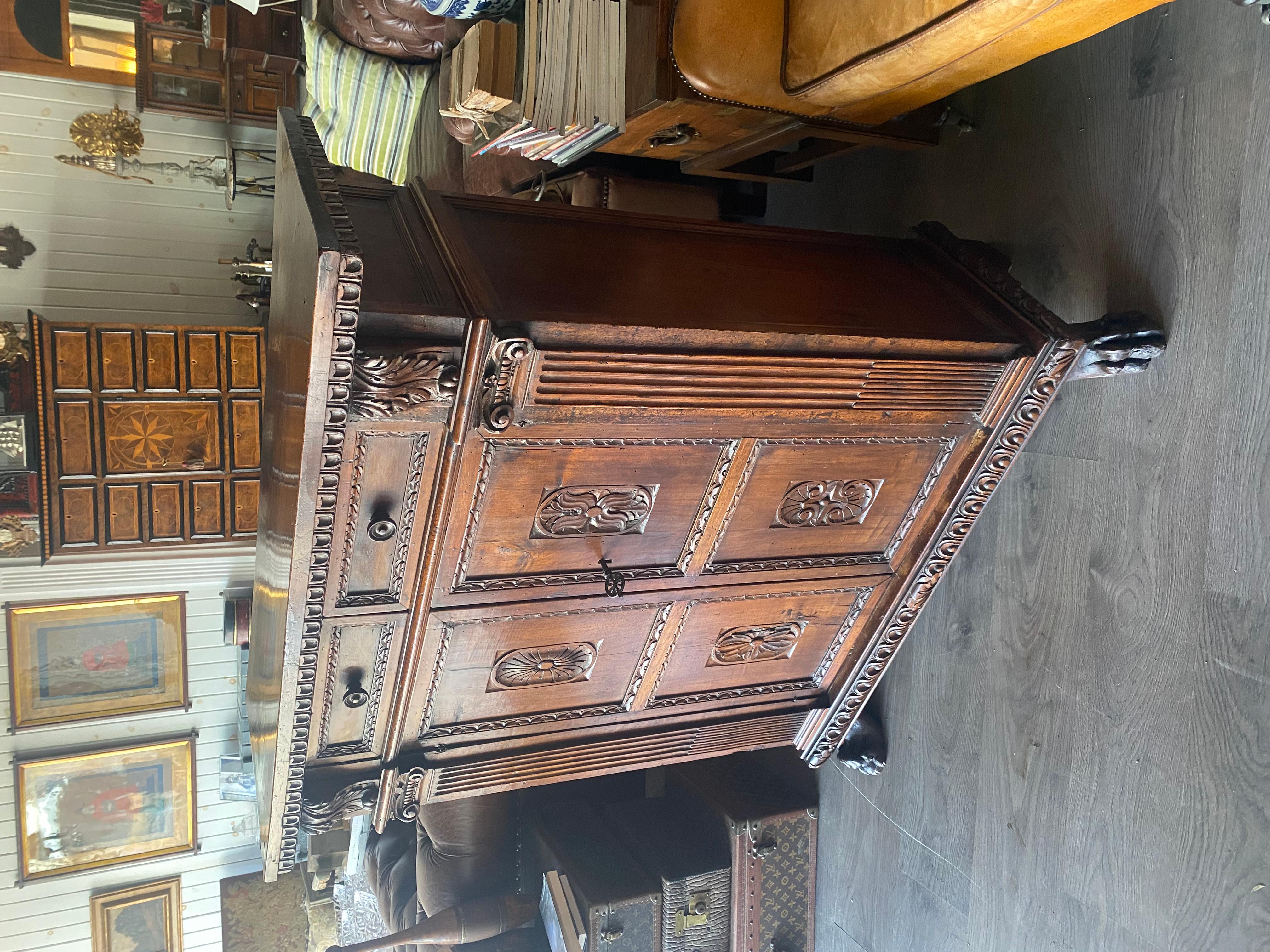 A tall walnut cabinet buffet, having a plank top with dentil moulding above a two drawers. The carved paneled doors, flanked by Doric columns sitting on multi-moiled base, supported with wonderfully carved lion paw feet on the front and bracket feet