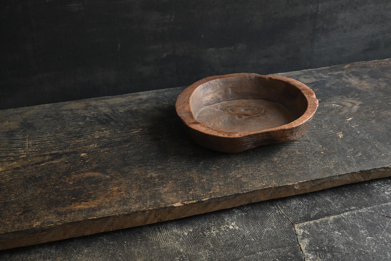 This wooden bowl is believed to have been made in Southeast Asia around the 20th century. It was owned by a Japanese antique collector, and its rugged yet warm shape is impressive.

It is made by hollowing out a single thick board, and is made of