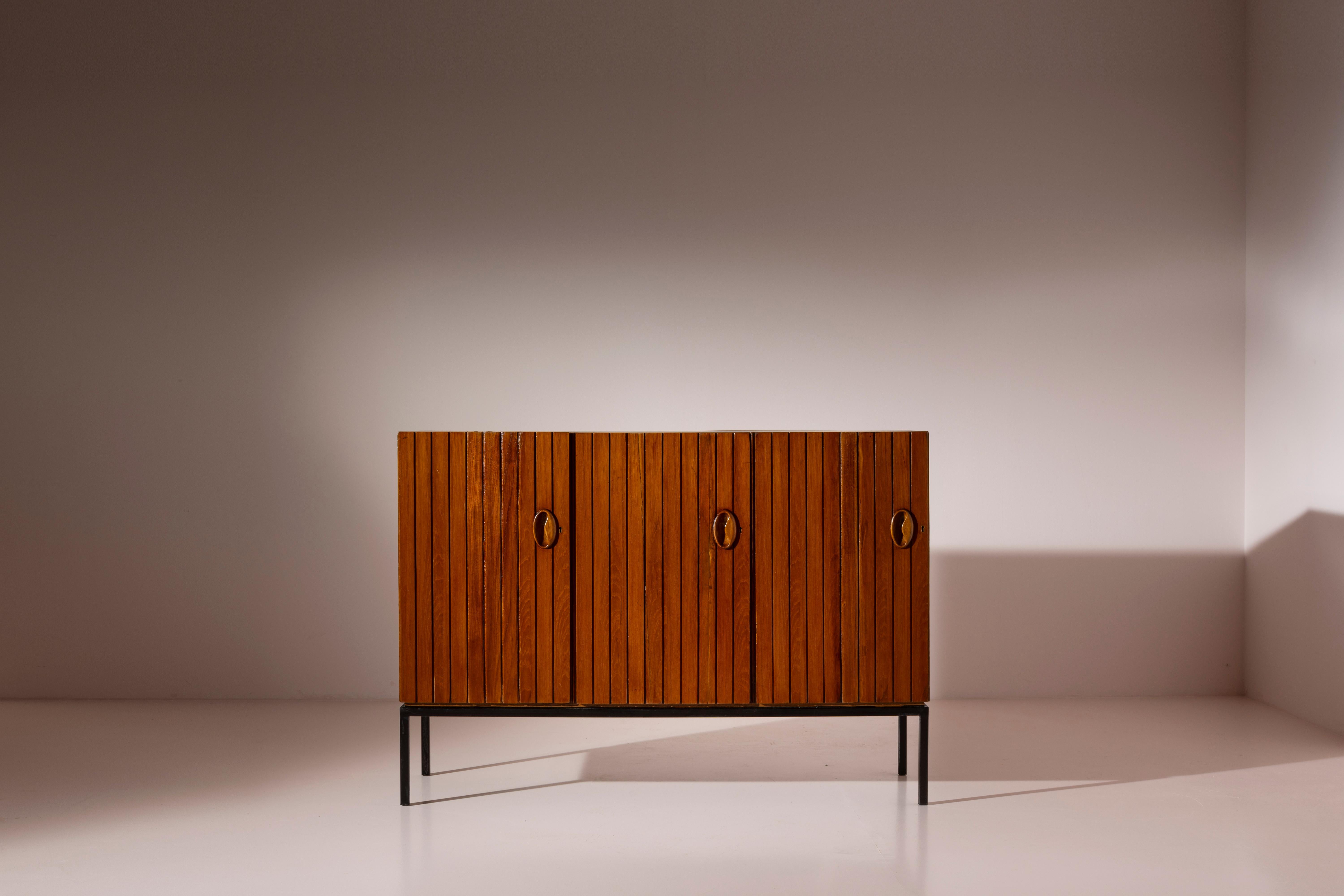 This sideboard, crafted from painted metal and teak, featuring internal doors and drawers, represents an exemplary piece of Italian craftsmanship under the distinguished marque 
