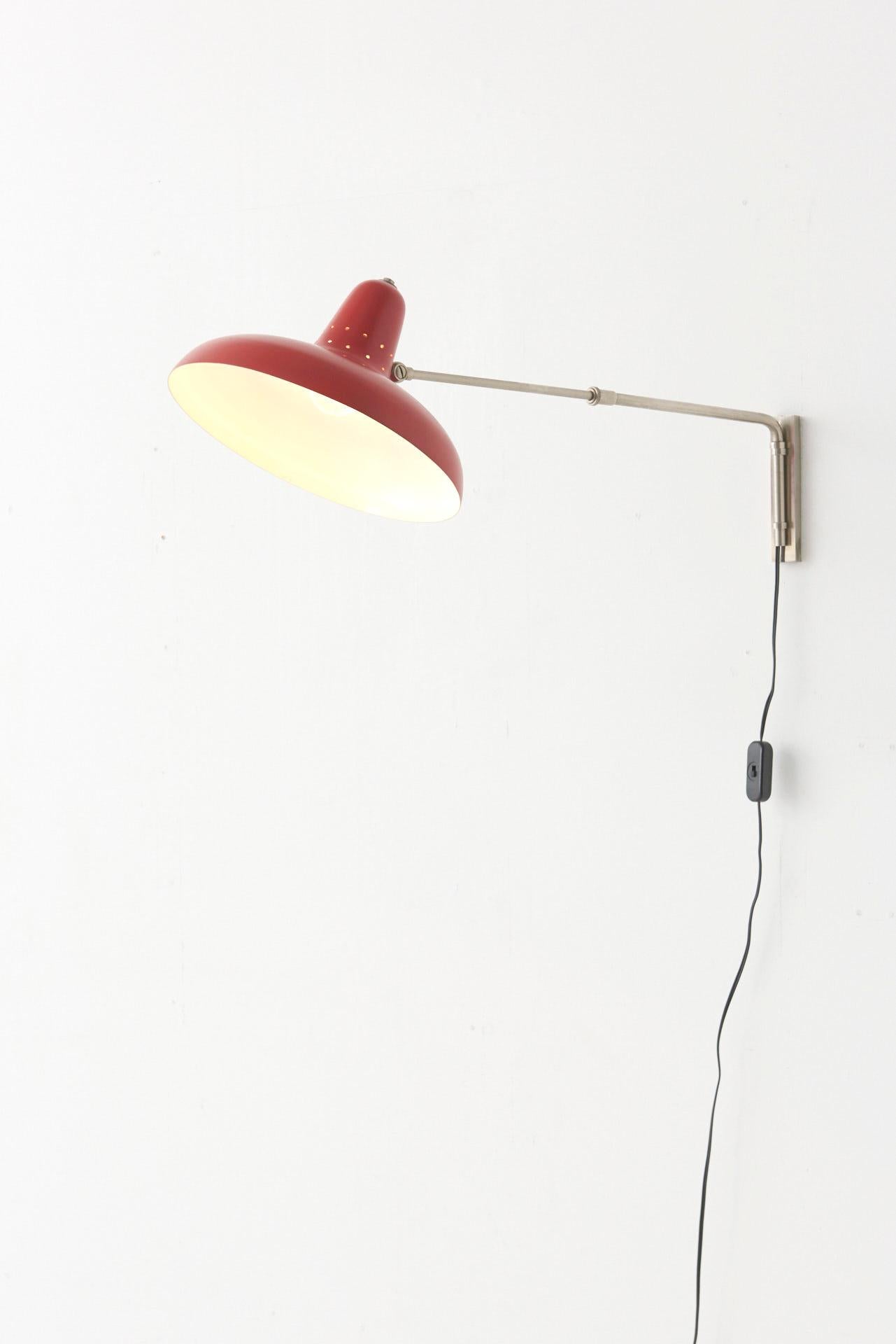 A telescopic wall lamp designed by H.Fillekes in 1958.  The lamp has a red lacquered lamp shade with small perforations. The telescopic arm is made of nickel plated steel and has a range between of 20cm, between 67cm and 87cm. The lamp is