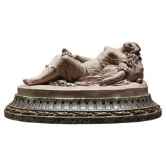 A Terracotta Group of a reclining scantily clad maiden with her dog
