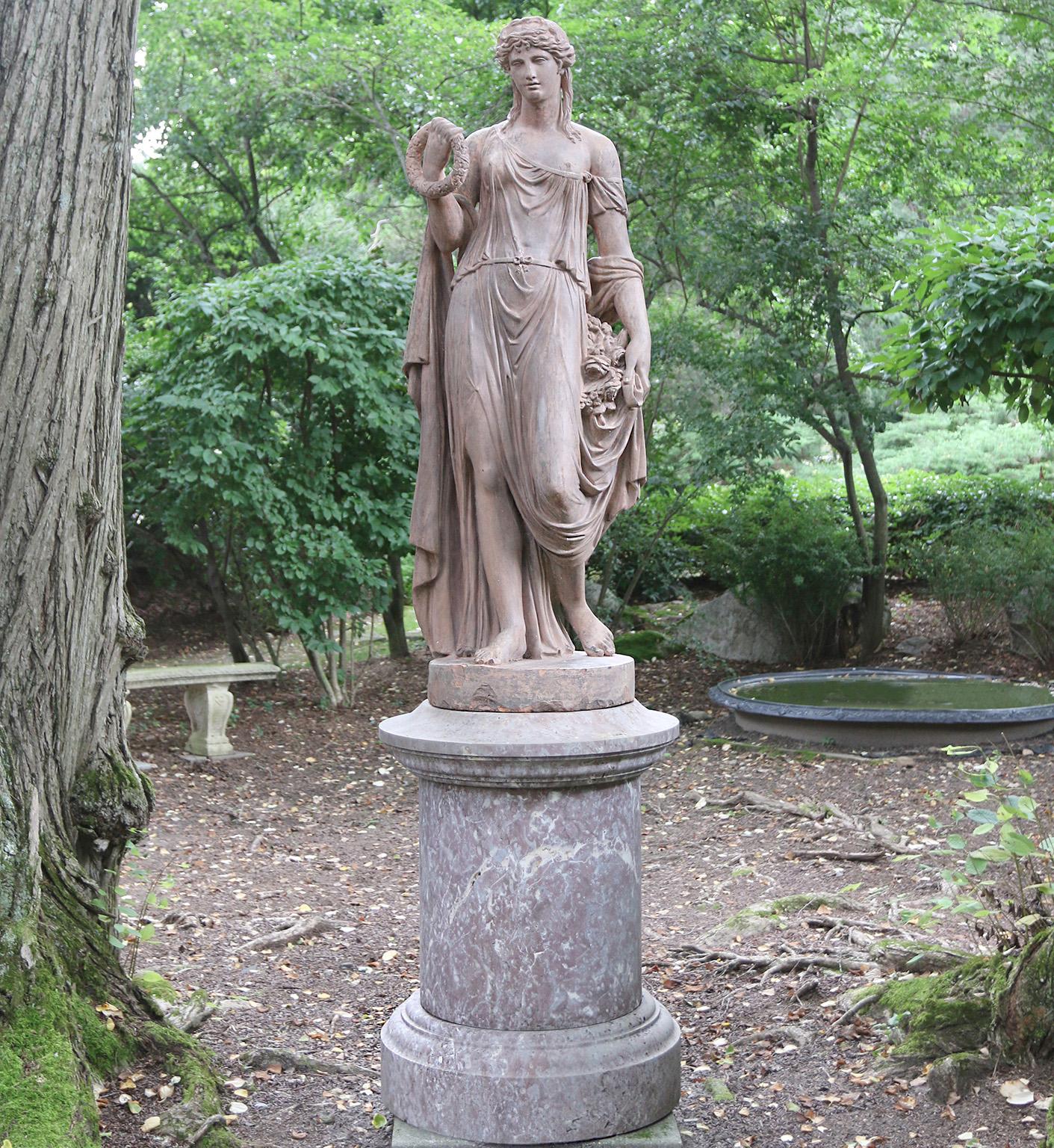 Eine schöne und seltene Terrakotta-Figur der Flora in Kontrapost-Pose, klassisch gekleidet mit hochgestecktem und gelocktem Haar, mit einem Blumenkranz in der rechten Hand der Figur und einem Blumenstrauß in der linken Hand. Das Gesicht der Figur