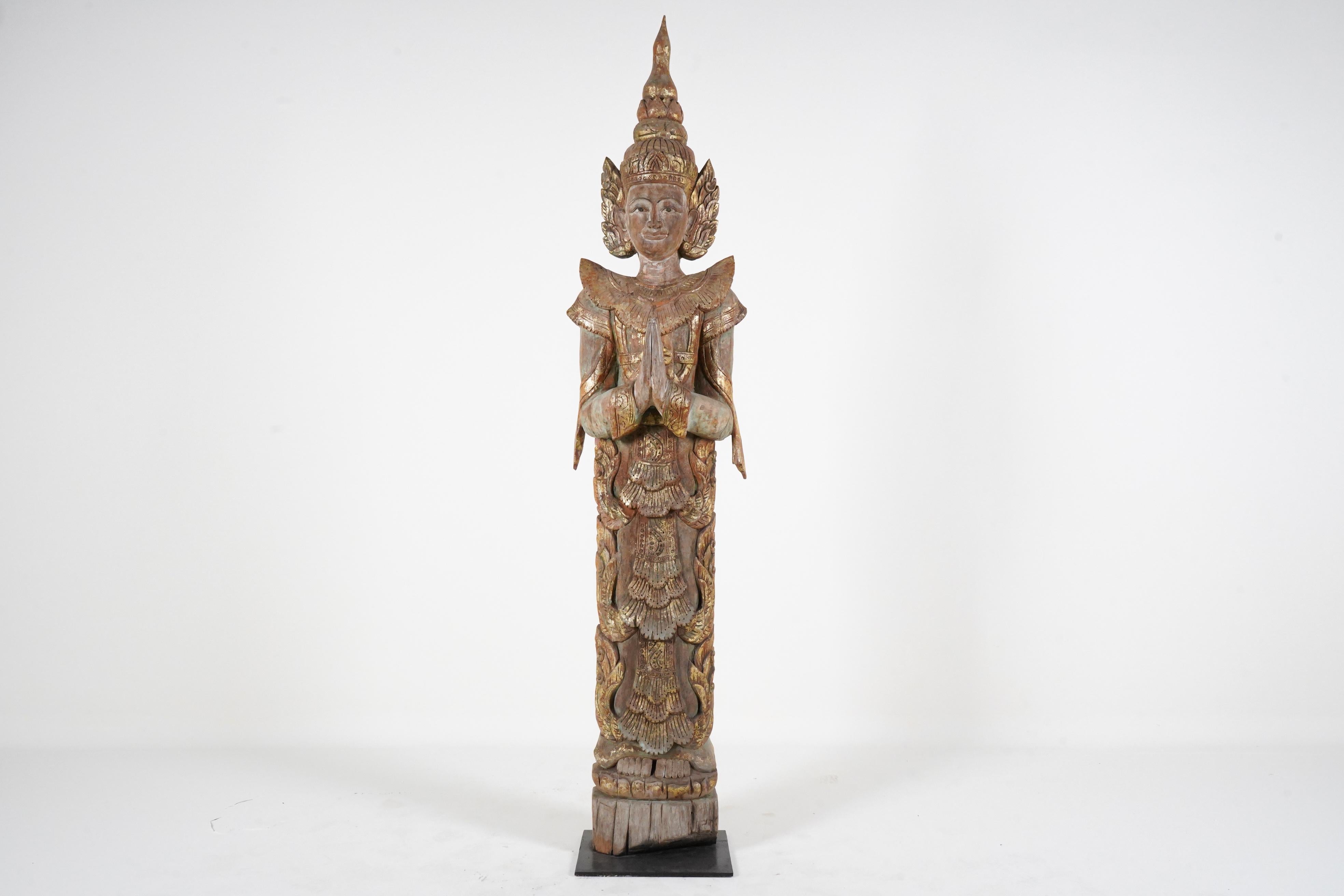 Thai temples often contained various kinds of carved figures including Buddhas, apostles and angels. This large greeting angel is based on sculptures that typically flanked altars or entrances. Thai Buddhists, like members of other faiths, believe