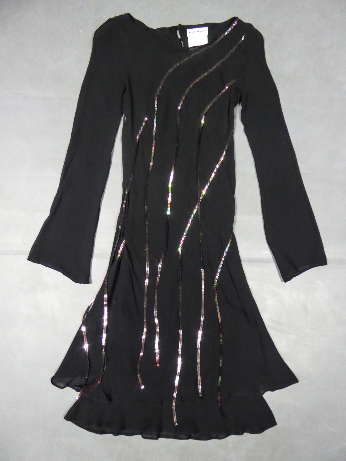 Circa 2000
France

Little Black Cocktail Dress in black silk crepe decorated with long iridescent sequined fringes by Thierry Mugler and dating from the 2000s. Short dress with round collar and long sleeves widened at the wrists. Appliqué fringes of