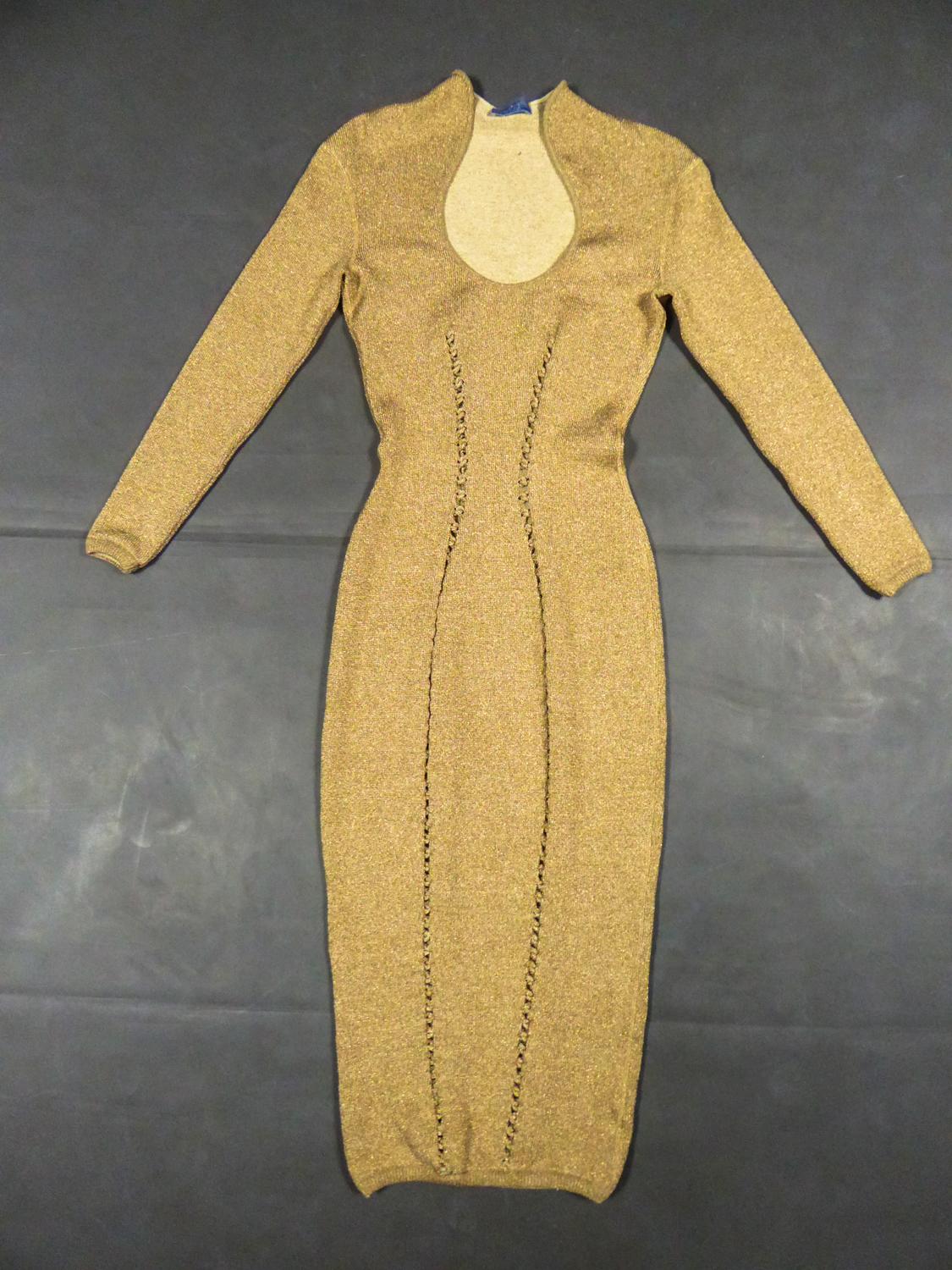 Circa 1990/2000
France

Long evening dress in golden lurex chiné knitwear and stretch cream wool by Thierry Mugler from the years 1990/2000. Stretch and skin-tight dress with plunging neckline, small turn up collar and long sleeves. Interlacing work
