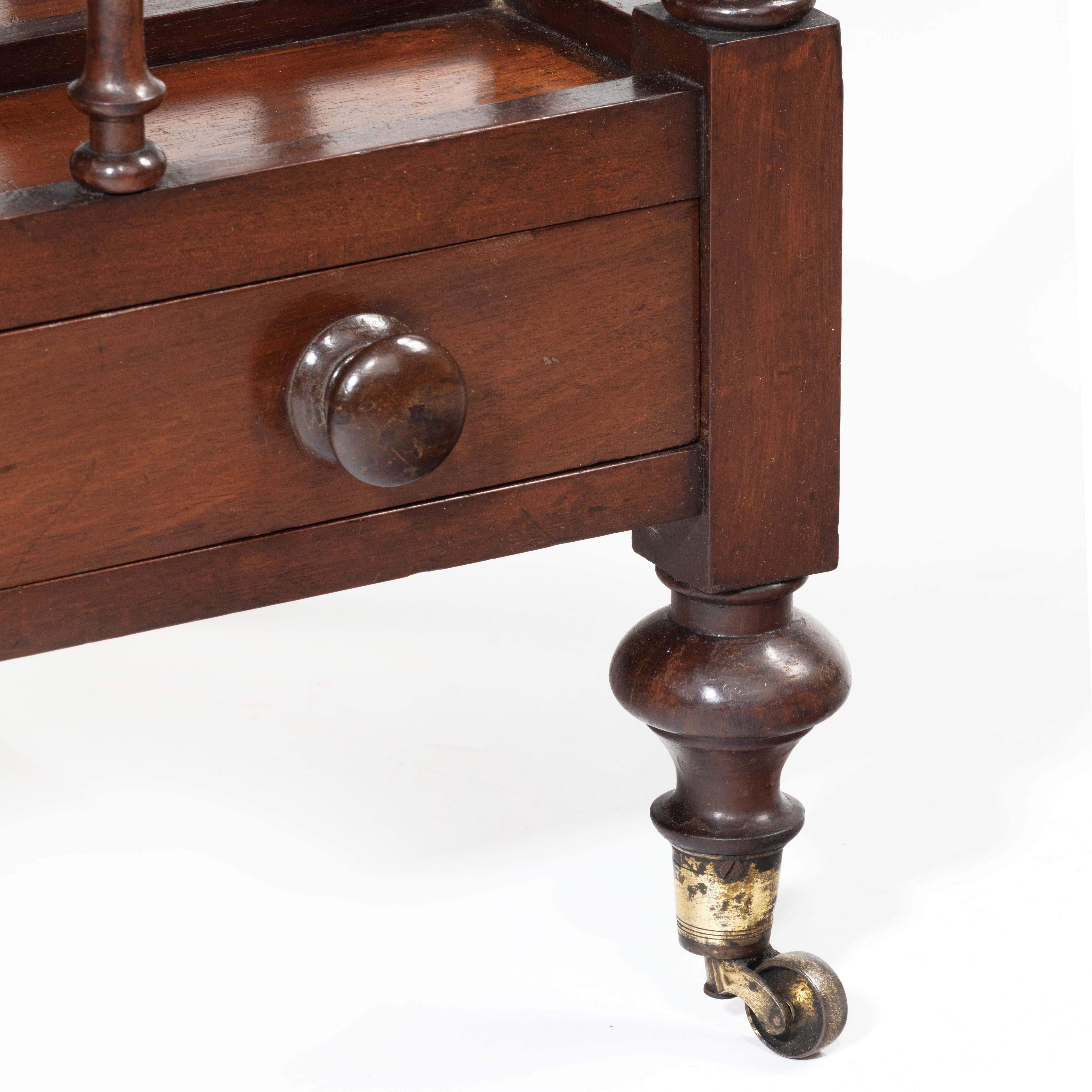 A three division boat-shaped mahogany Canterbury by Bentley, with turned spindles and spinning top feet with the original brass castors, the drawer to the frieze with wooden knop handles. Signed on the bottom of the drawer ‘Bentley, Stoke’, English,