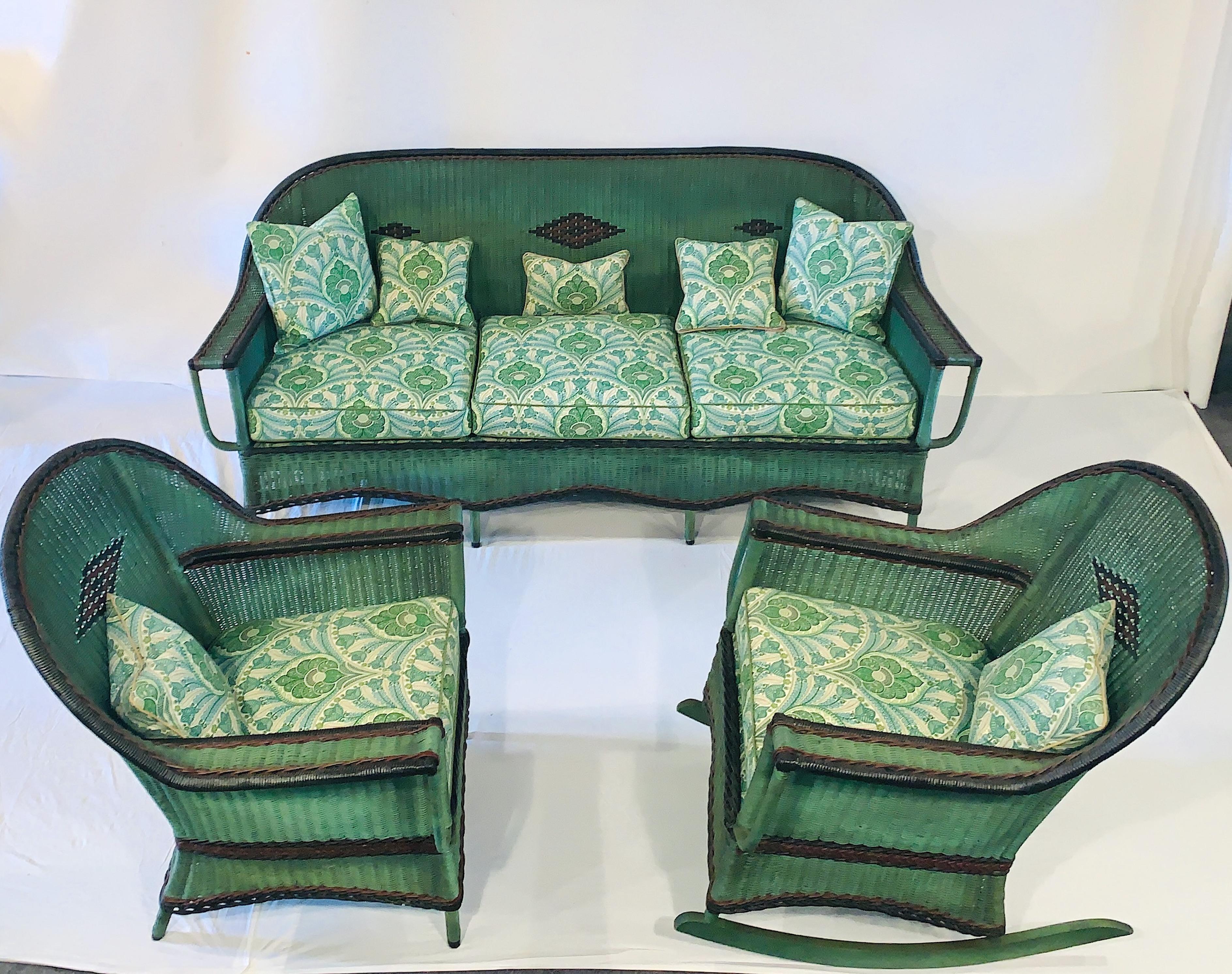 A beautiful matching close woven parlor or porch suite of Antique American Wicker consisting of a large three seat sofa ,a large matching armchair and a large comfortable relaxing rocking chair. The set is done in a stylish almost French green