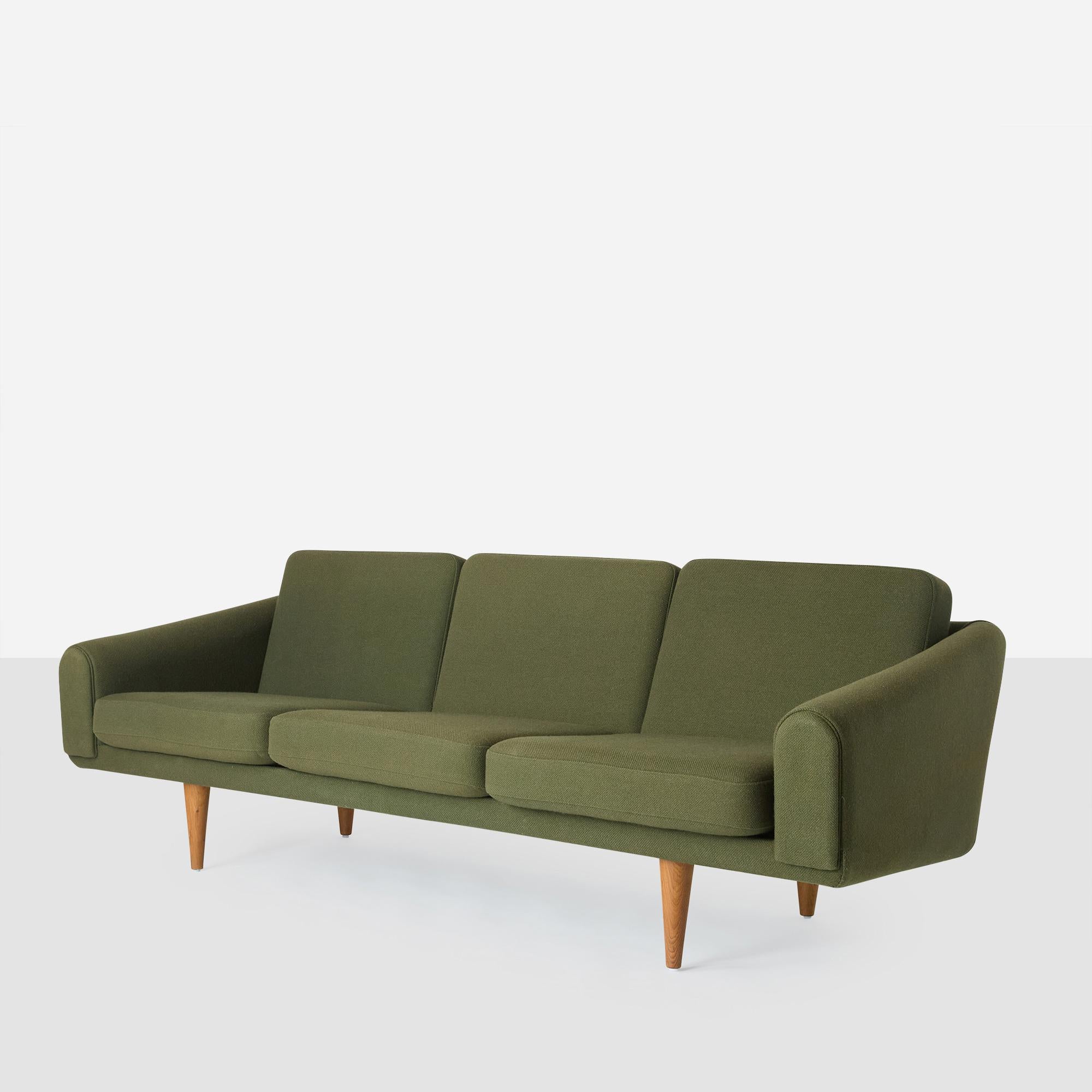 A three seat sofa attributed to Illum Wikkelso for Mikael Laursen. Covered in green wool with oak legs.