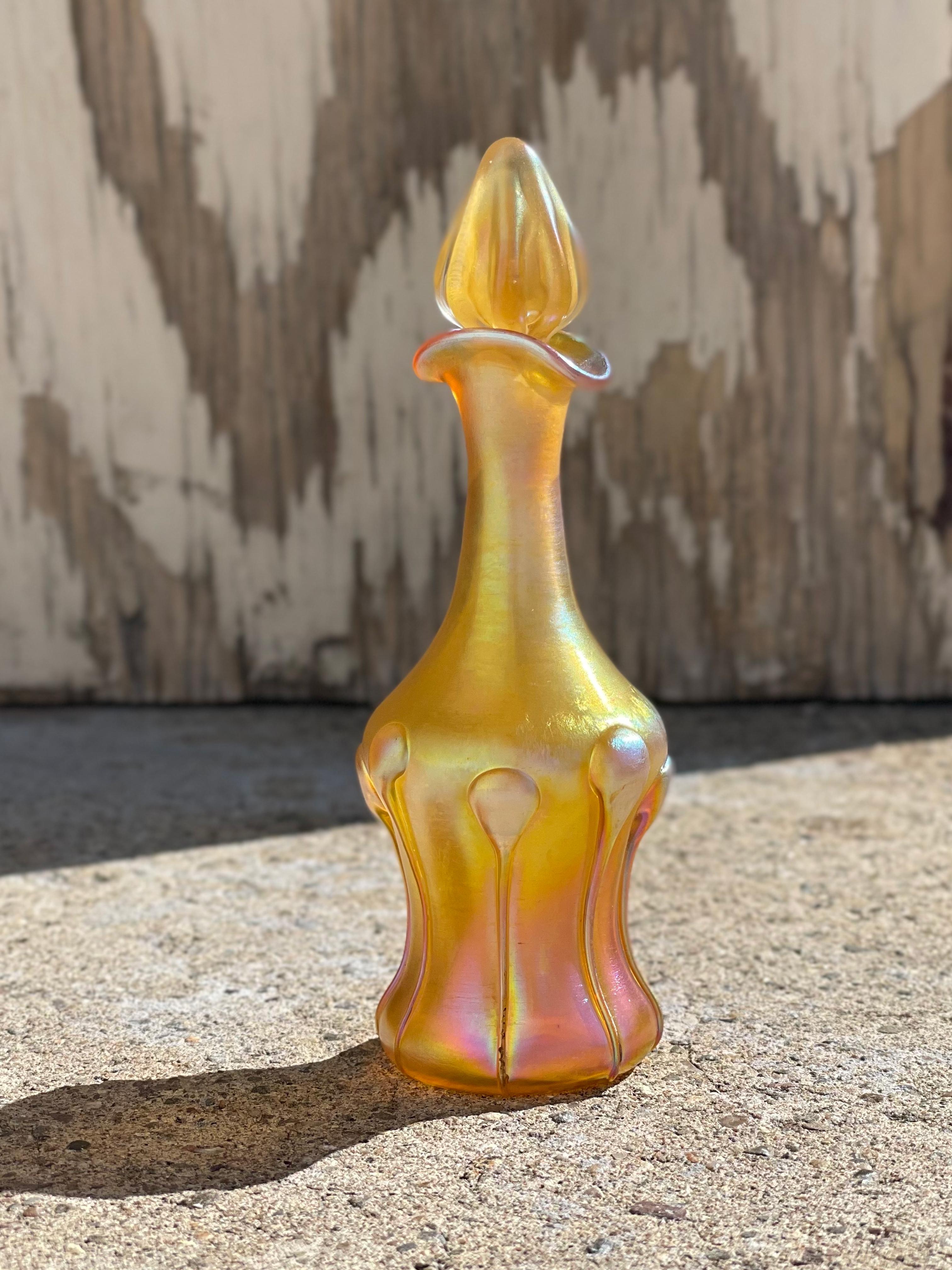 An early 20th century American Art Nouveau blown glass and applied perfume bottle by, Tiffany Studios decorated with applied tadpole decoration against a heavily iridescent gold background retaining its original stopper. The bottle is signed,