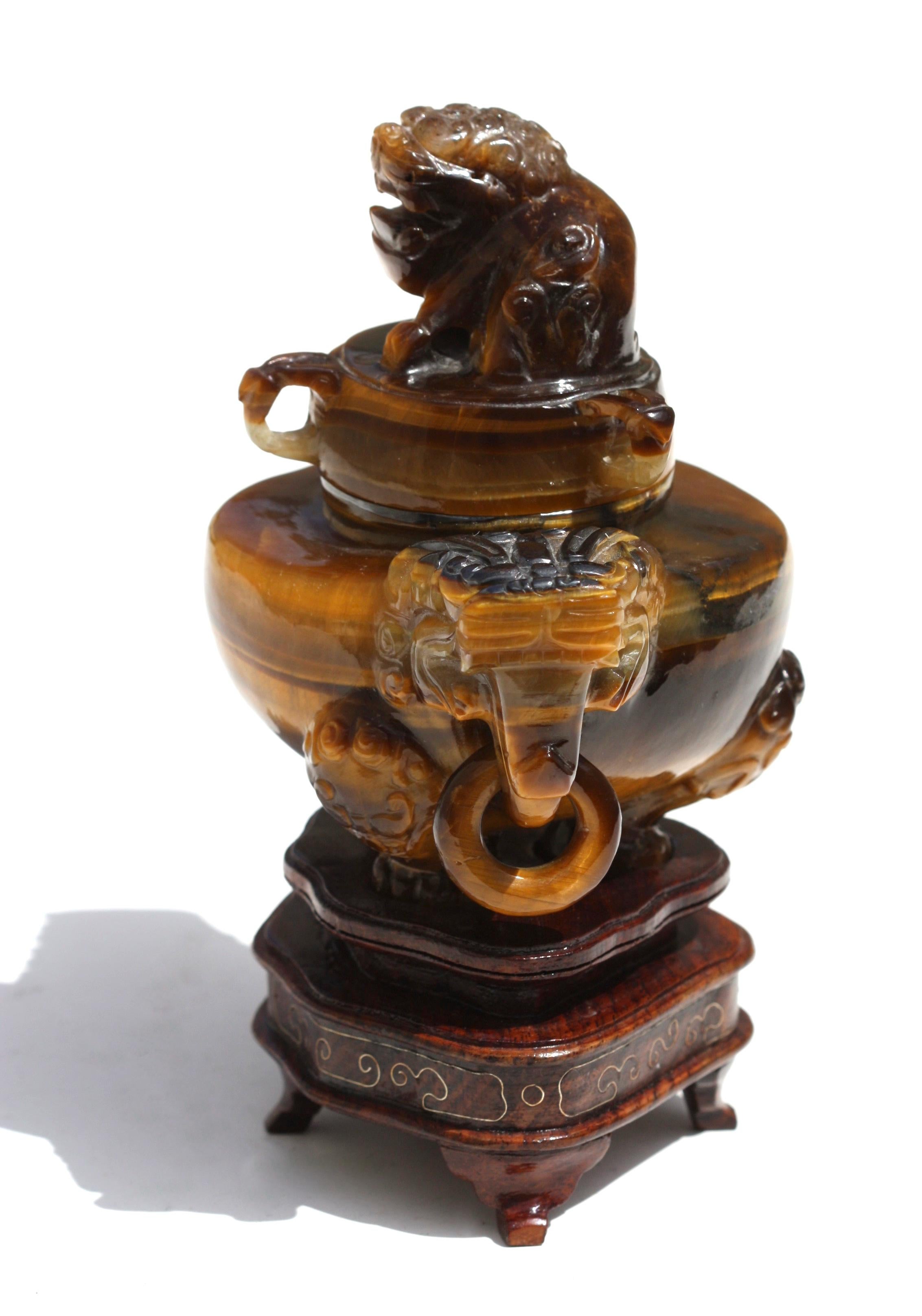 A Tiger's eye tripod incense burner and cover
Chinese, 20th century
of compressed globular form raised on three cabriole legs issuing from lion masks, flanked by two horned mythical-beast handles suspending loose rings, 
the smoothly polished