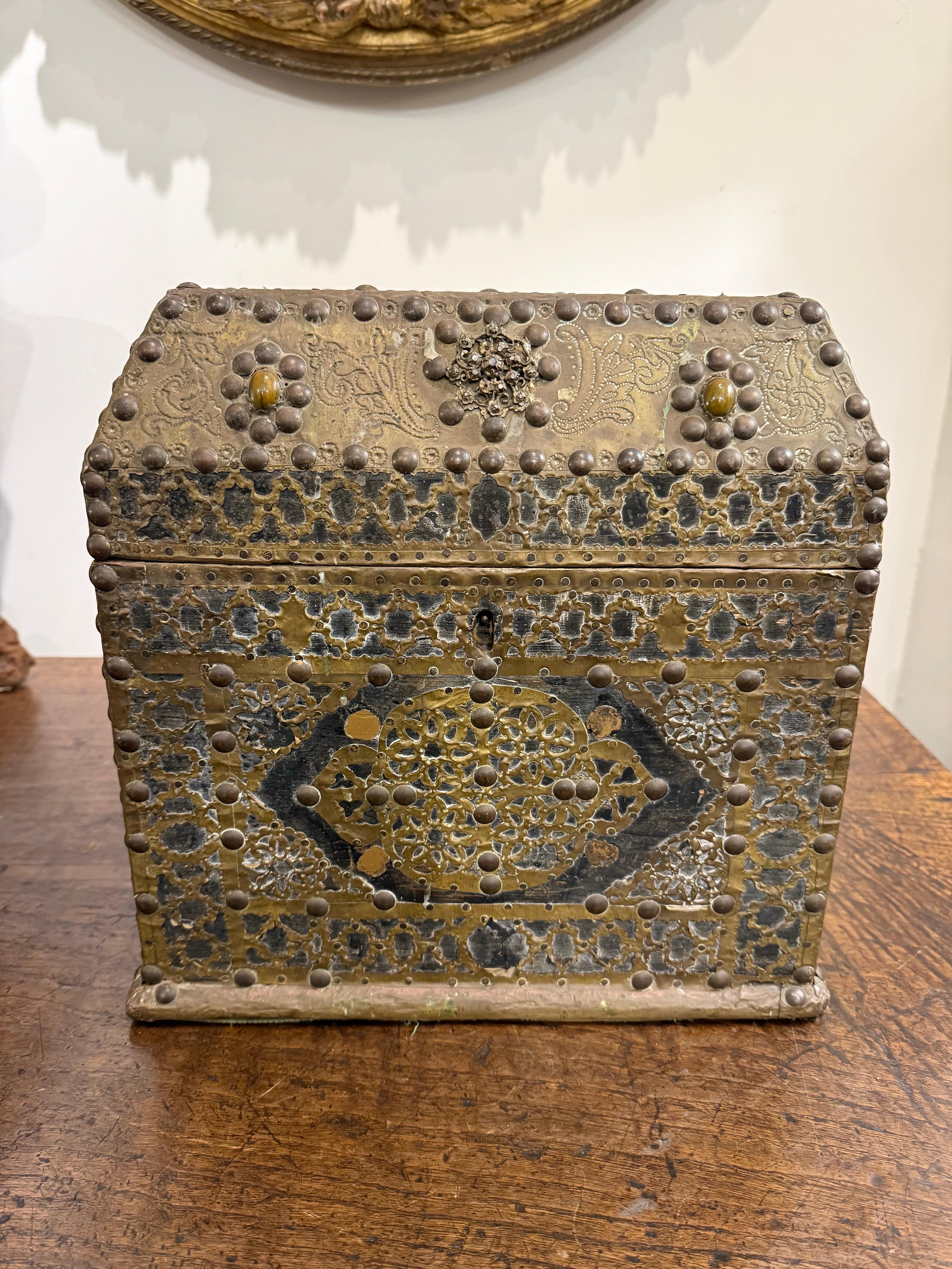 A Timber Gilt-Metal Embellished Box, 19th Century

Description:
The wooden surface decorated with gilt-metal embellishments, including floral and foliate motifs, punctuated by nailhead bosses, with a hinged chamfered rectangular lid joined by hinges