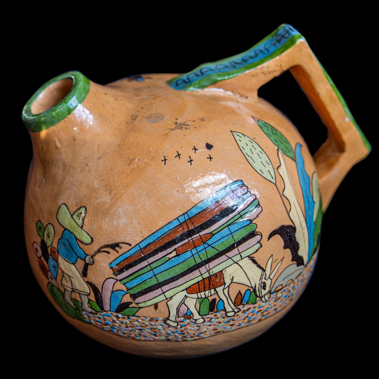 A wonderfully decorative earthenware jug from the Tonala valley, depicting a ‘Tlaquepaque’ scene with the most beautiful glazed artisanal composition. Graphic vivid colours depicting sleepy chaparral life, cacti and flora. In the 20s and 30s just