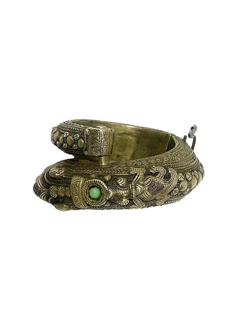 A Toba Batak Indonesian bracelet, ca 1900

A bracelet made of brass in the shape of an elephant head with trunk with a green stone on the neck followed by a salamander, the rest with round ornate decorations. A pin is missing. The bracelet comes
