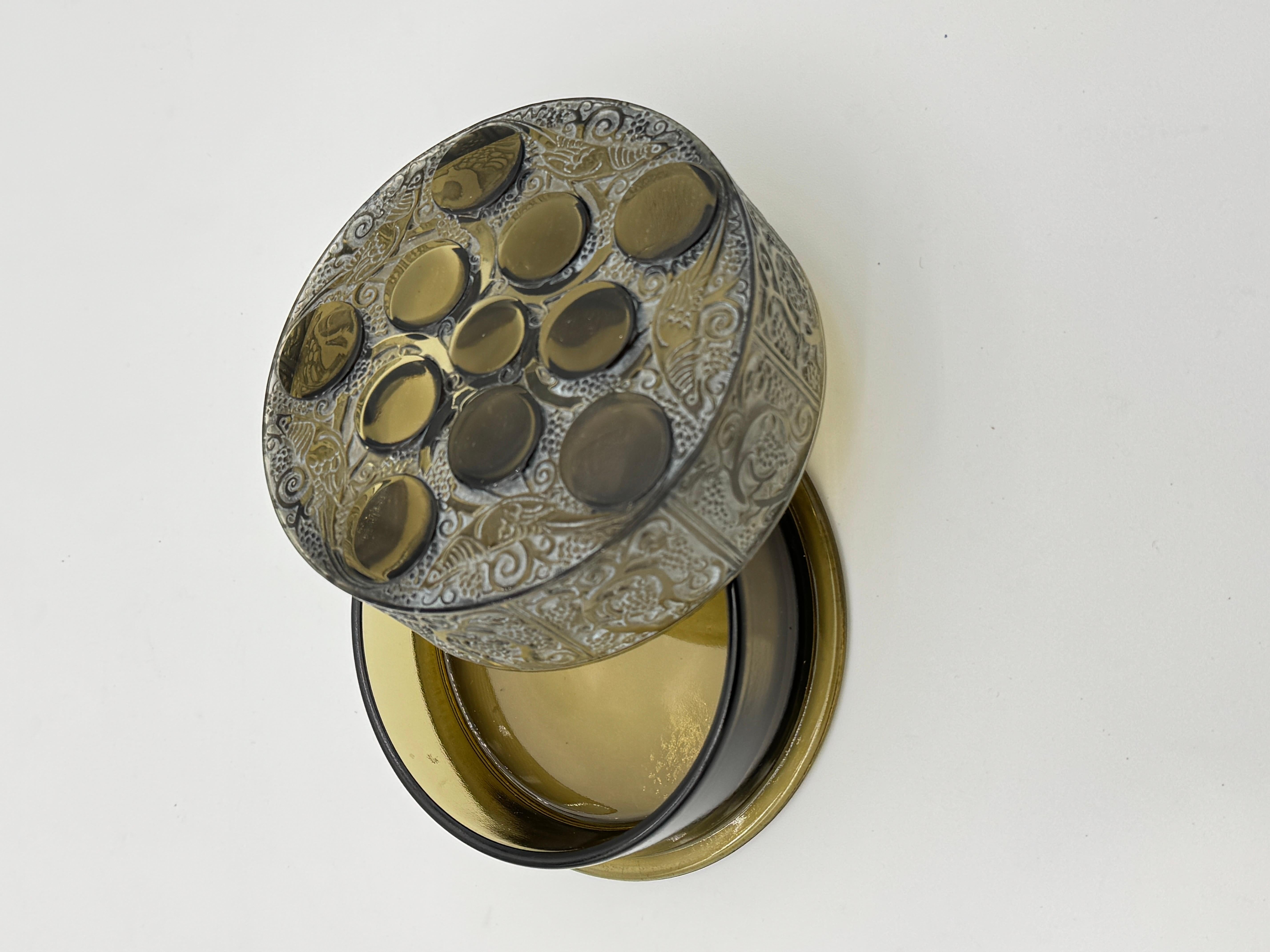 Il roger boxe è stato realizzato in vetro bianco nel 1926 da R.Lalique.

Questo esemplare è in vetro topazio con una forte patina bianca.

La scatola è in ottime condizioni con una firma stampata in stampatello sul coperchio della scatola.

La