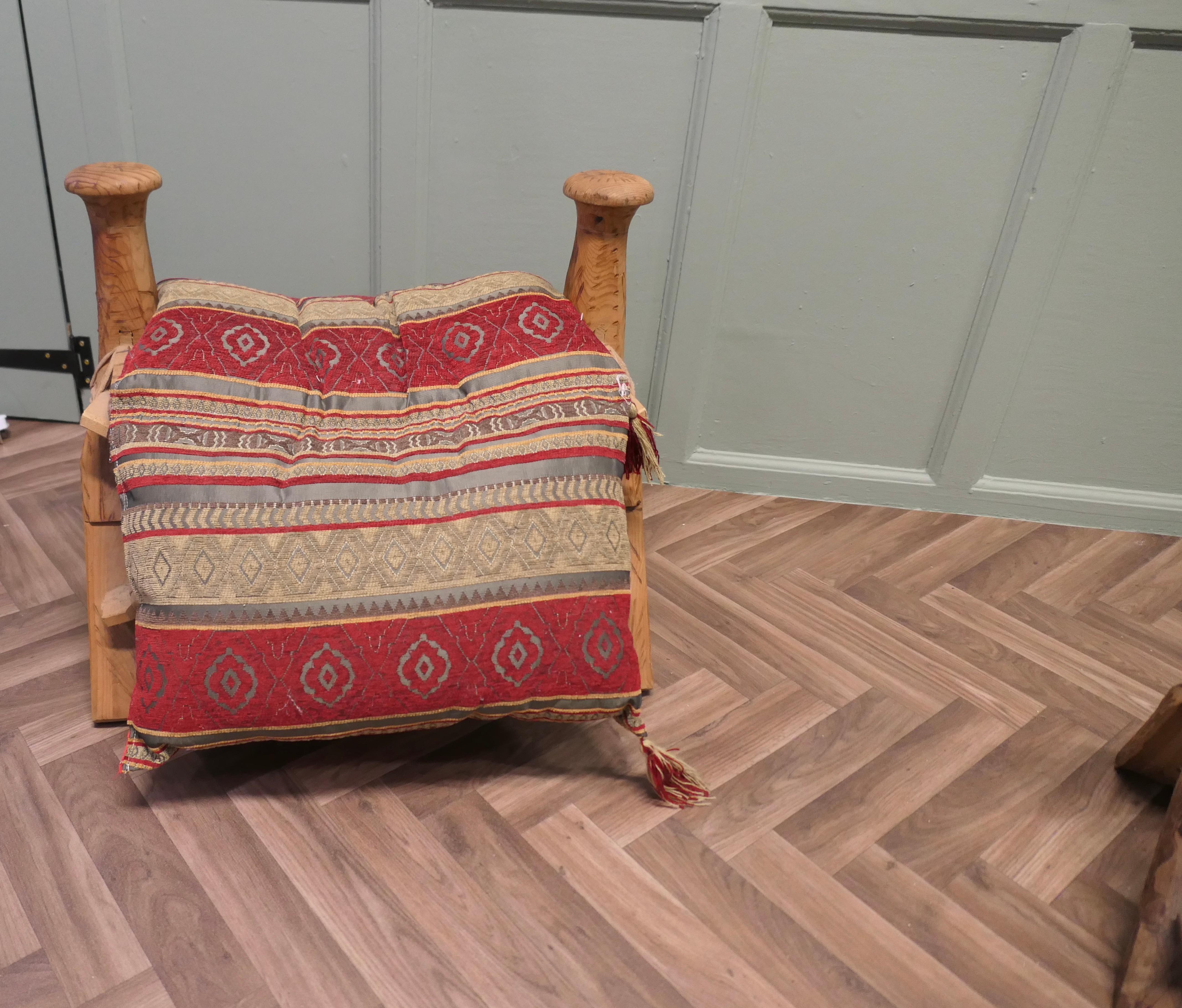 A Traditional Camel Saddle / Stool

A Traditional Camel Saddle constructed from several pieces of scratch carved olive wood, tied together with strips of hide to form a saddle stool with splayed supports and round pommels at each end, the saddle