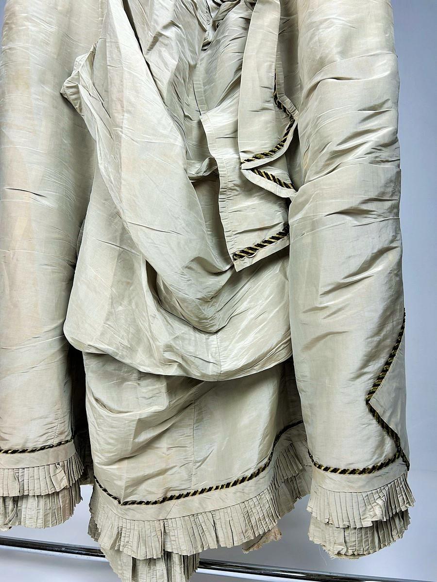 Circa 1885
France
Large lobster tail skirt forming the train of an elegant bourgeois woman from the beginning of the Third Republic around 1885. Lime or water green moiré silk faille with large religious pleats in front and large asymmetrical puffed