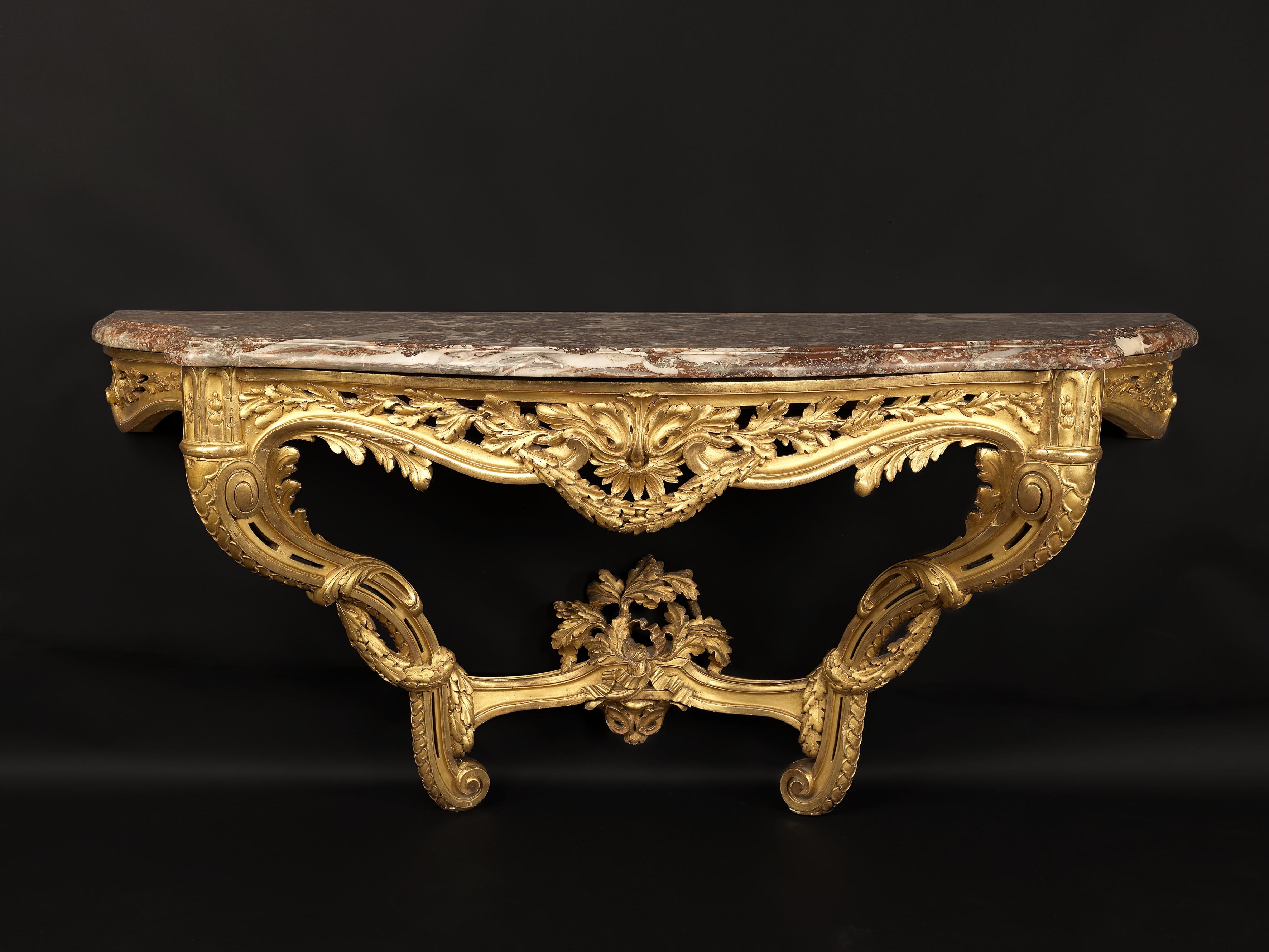 A fine transitional style carved giltwood console table with a Rouge de Rance marble top.

French, circa 1880. 

Of impressive proportions this finely carved console table has a shaped rouge de Rance marble top above a frieze carved with