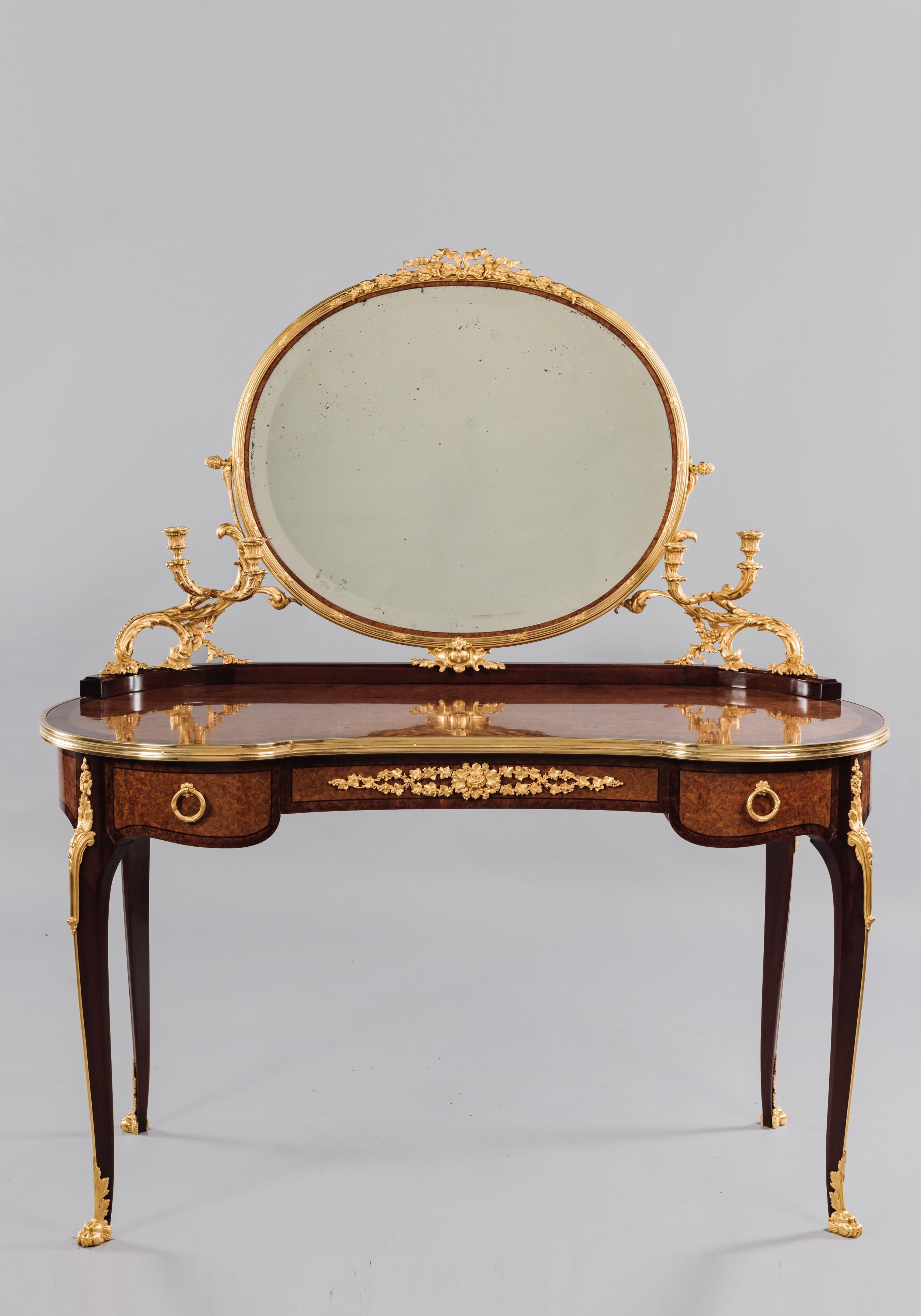 A transitional style gilt-bronze mounted Amboyna dressing table, attributed to François Linke.

French, circa 1900. 

This fine amboyna dressing table has a kidney shaped top with gilt-bronze encadrement and a superstructure supporting an oval