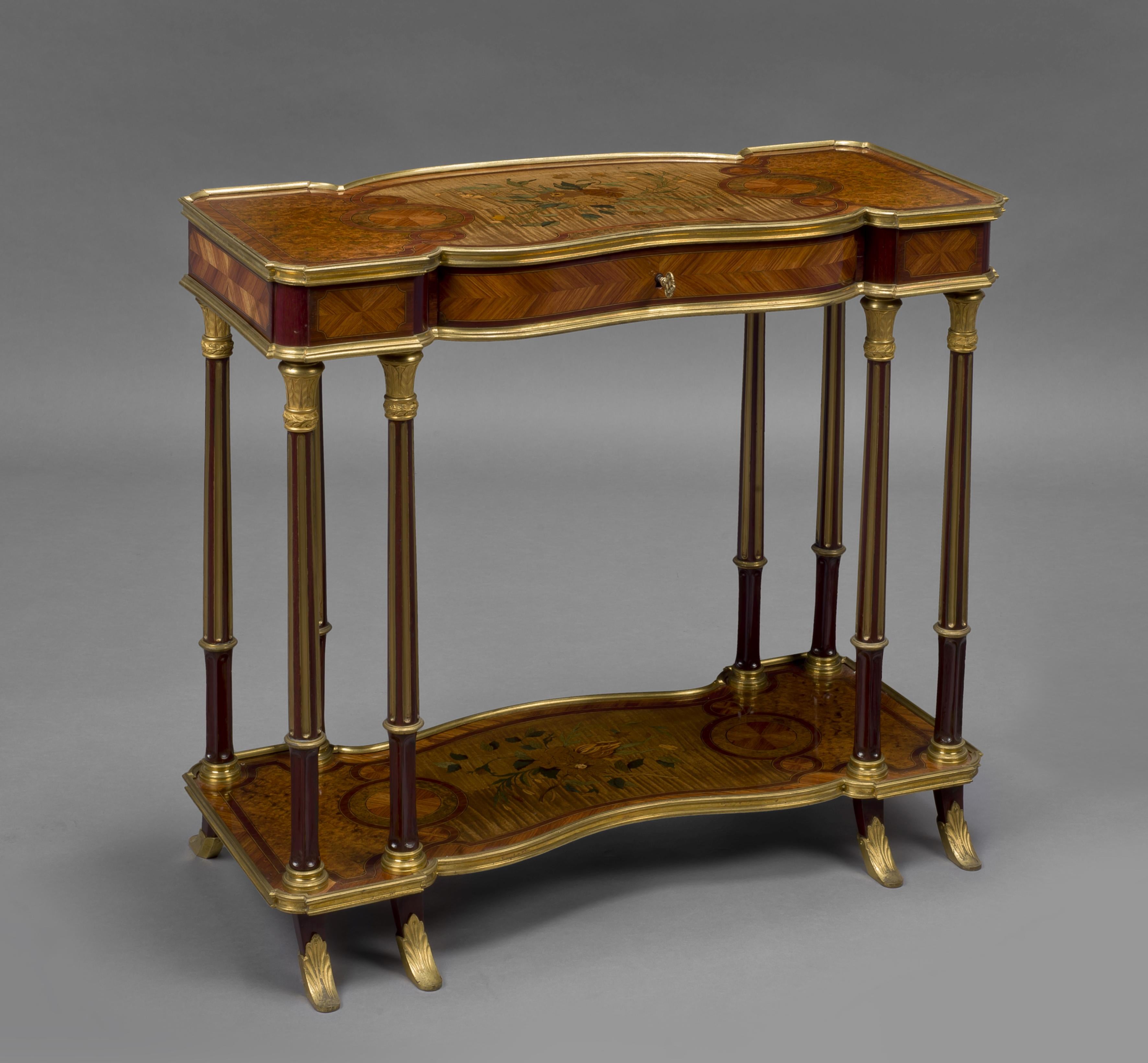 An unusual transitional style gilt bronze mounted low side table, attributed to Maison Krieger. 

French, circa 1880. 

This unusual table has a shaped top centred by an inlaid floral bouquet, above a frieze drawer. It is raised on eight