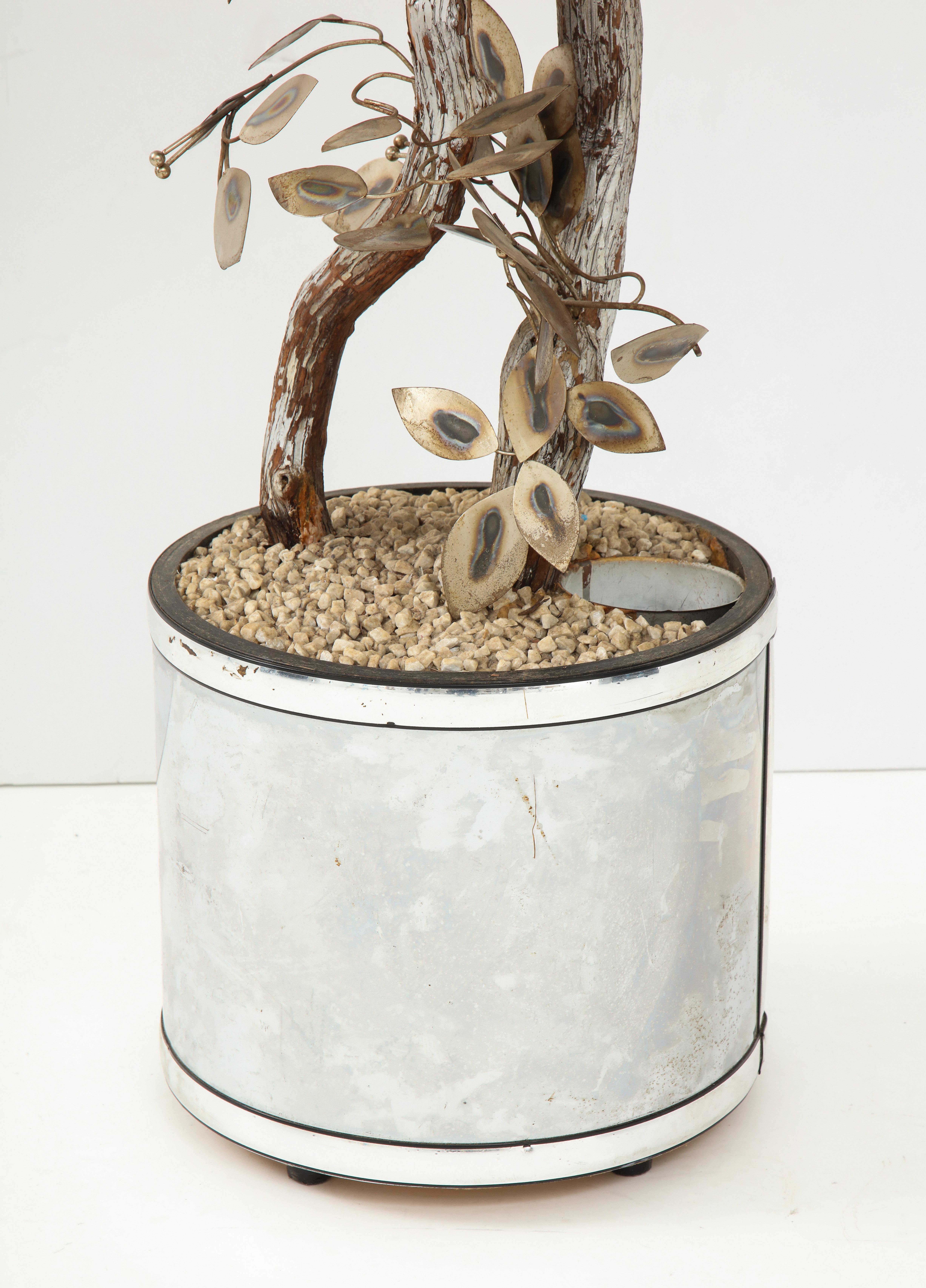 A great way to add dimension and whimsy to a room, this tree sculpture is a creation of Curtis Jeré. Standing six feet tall, the tree consists of silvered leaves on a silver painted tree branch in a silver planter. The tree is illuminated which adds