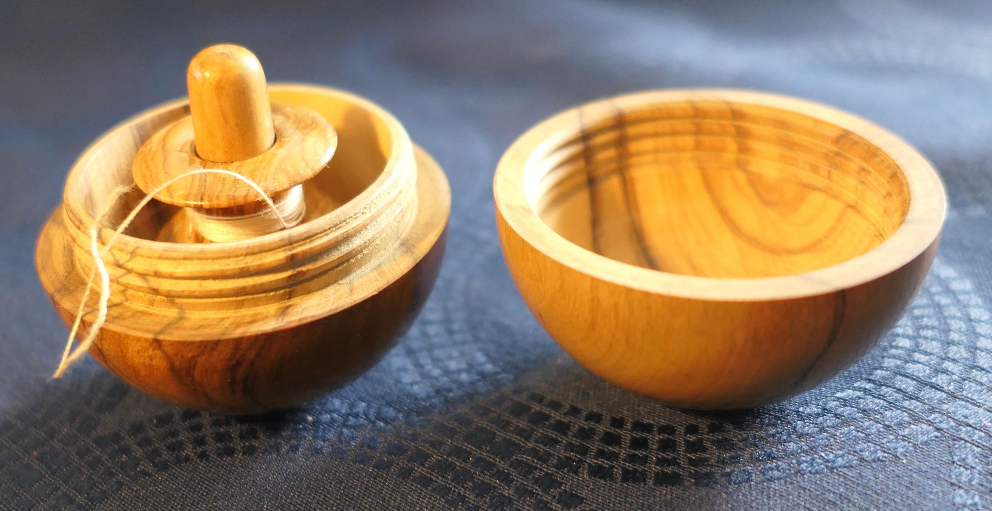 A Treen Sphere Enclosing Needle and Thread Spool

A wonderful piece when unscrewed to open it reveals inside a needle case at the centre and a double thread spool which slips over it
Beautifully and skilfully turned from olive wood 
The closed
