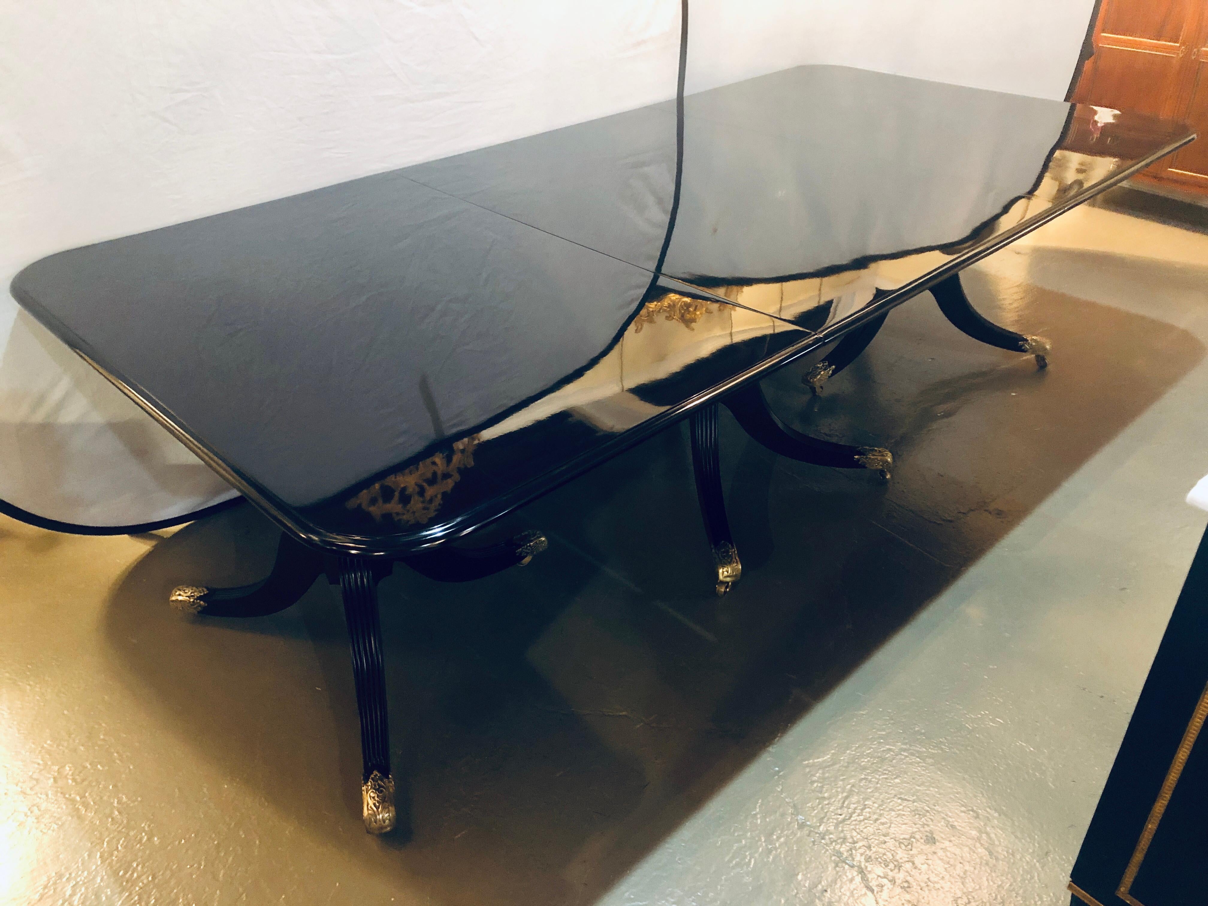 A Hollywood Regency triple pedestal circa 1920s ebony dining table in the manner of Maison Jansen. A truly stunning Steinway ebony finished triple pedestal dining table having two 15.5 inch leaves that extend to a full 132 inches long by 48.25