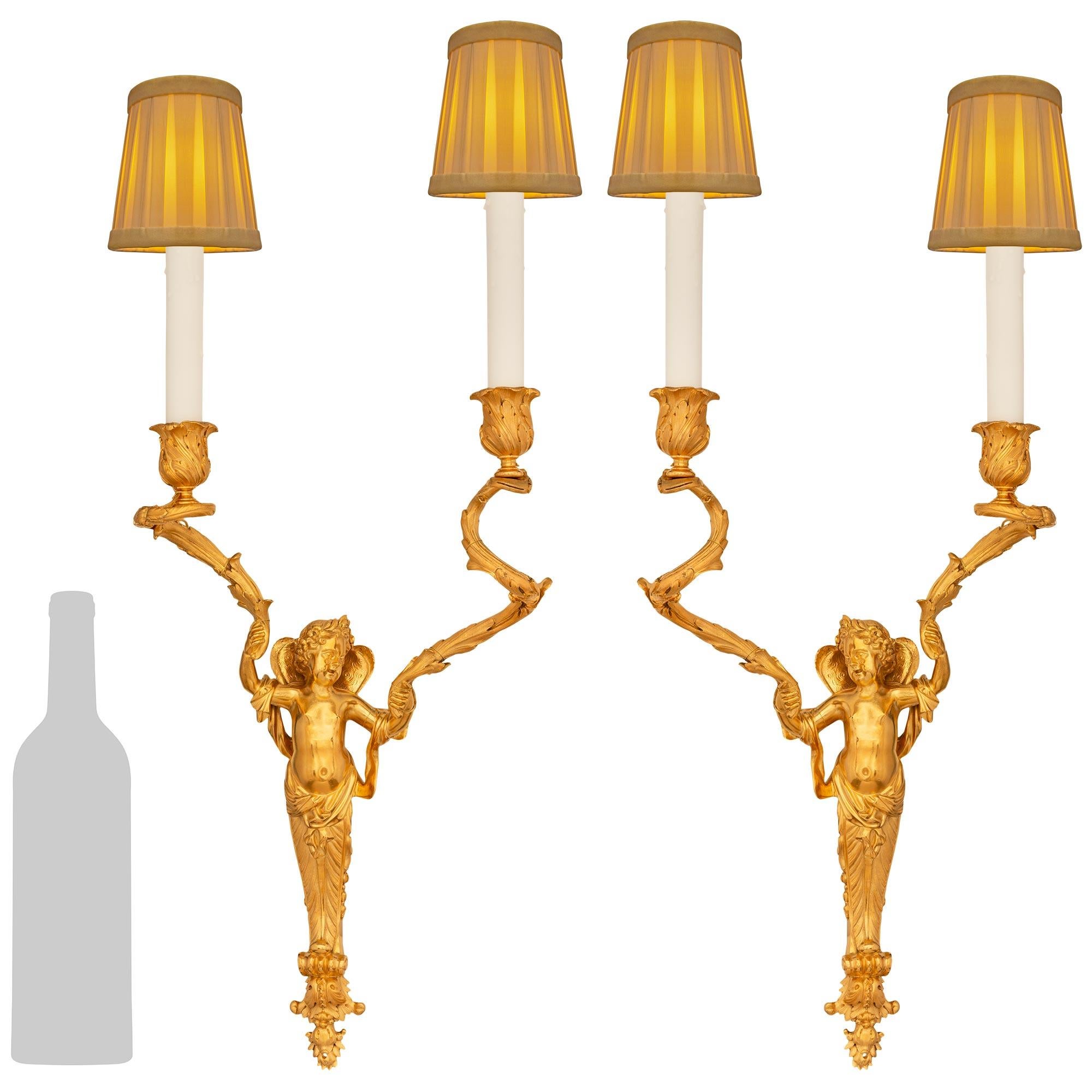 Preciosa y elegantísima pareja de auténticos apliques franceses de Ormolu del siglo XIX, estilo Luis XVI. Cada bello candelabro de dos brazos está centrado por remates inferiores decorados con follaje que sirven de plataforma para el querubín de