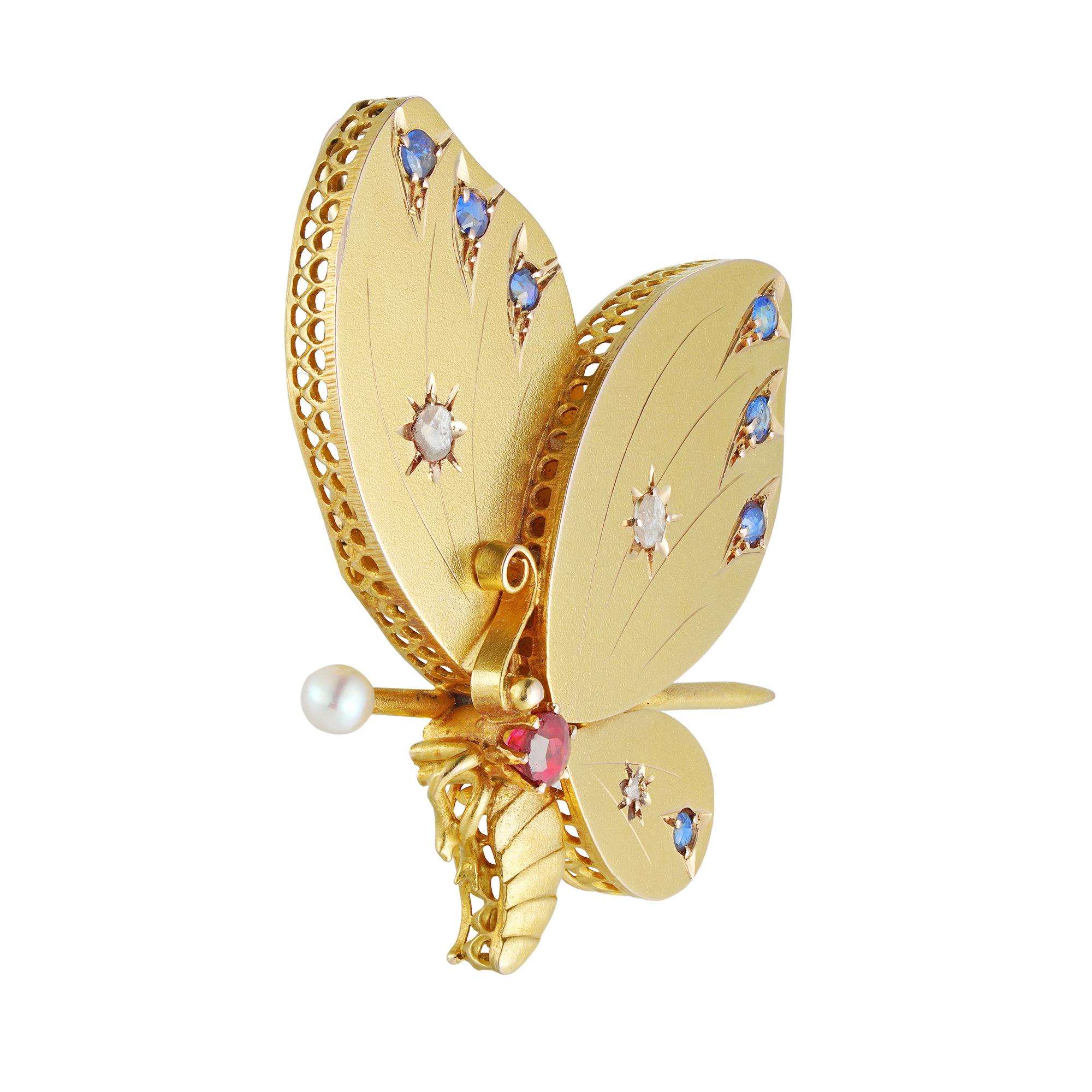 A turn-of-the-century gold butterfly brooch/pendant, the thorax set with a round faceted ruby, the wings embellished with three rose-cut diamonds and seven faceted sapphires, all mounted in yellow gold, with a gold pin set with a pearl, at the back