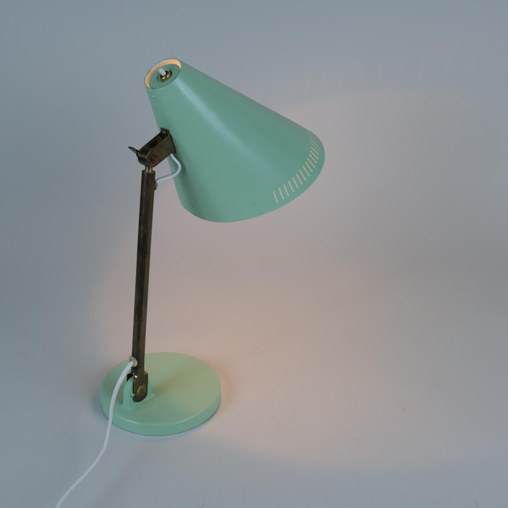 Cette lampe de table modèle 9222 de Paavo Tynell est un modèle durable et pratique présentant un mélange de 3 matériaux métalliques différents. Dans ce modèle, une tige ferme en laiton soutient un abat-jour conique en aluminium. La teinte est en