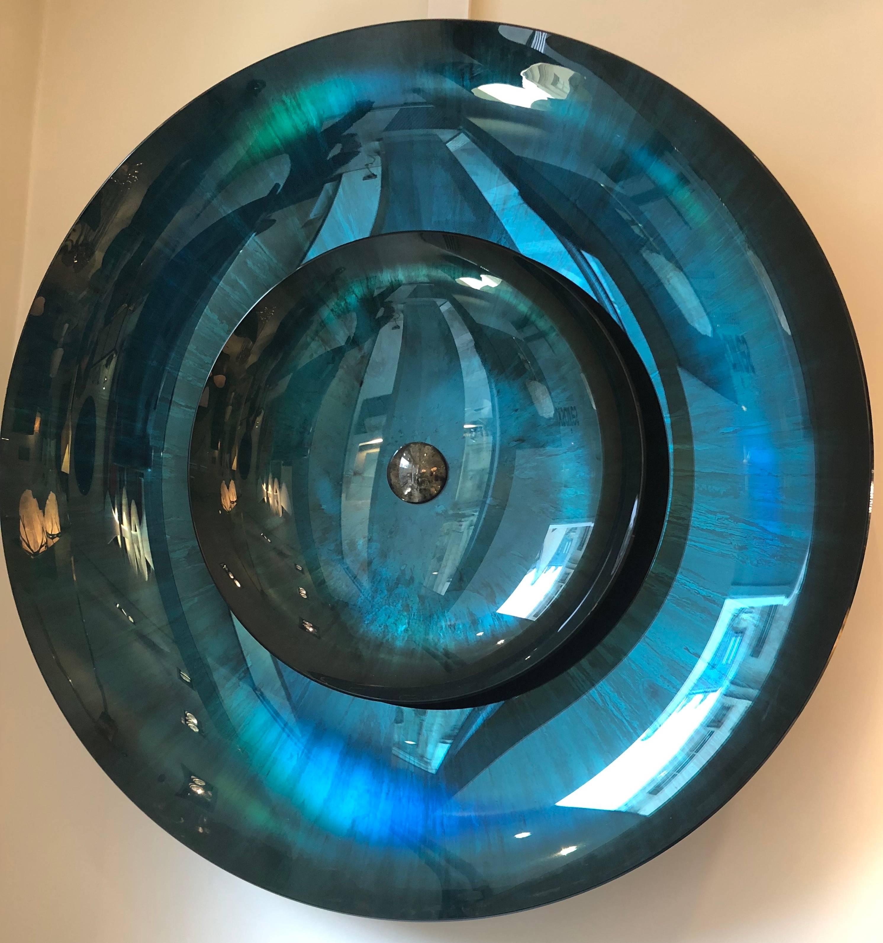 A turquoise tinted concave double mirror, with golden glass block in center, the brass mount is signed by the artist. Unique piece. Measures: diameter 107 cm.

 