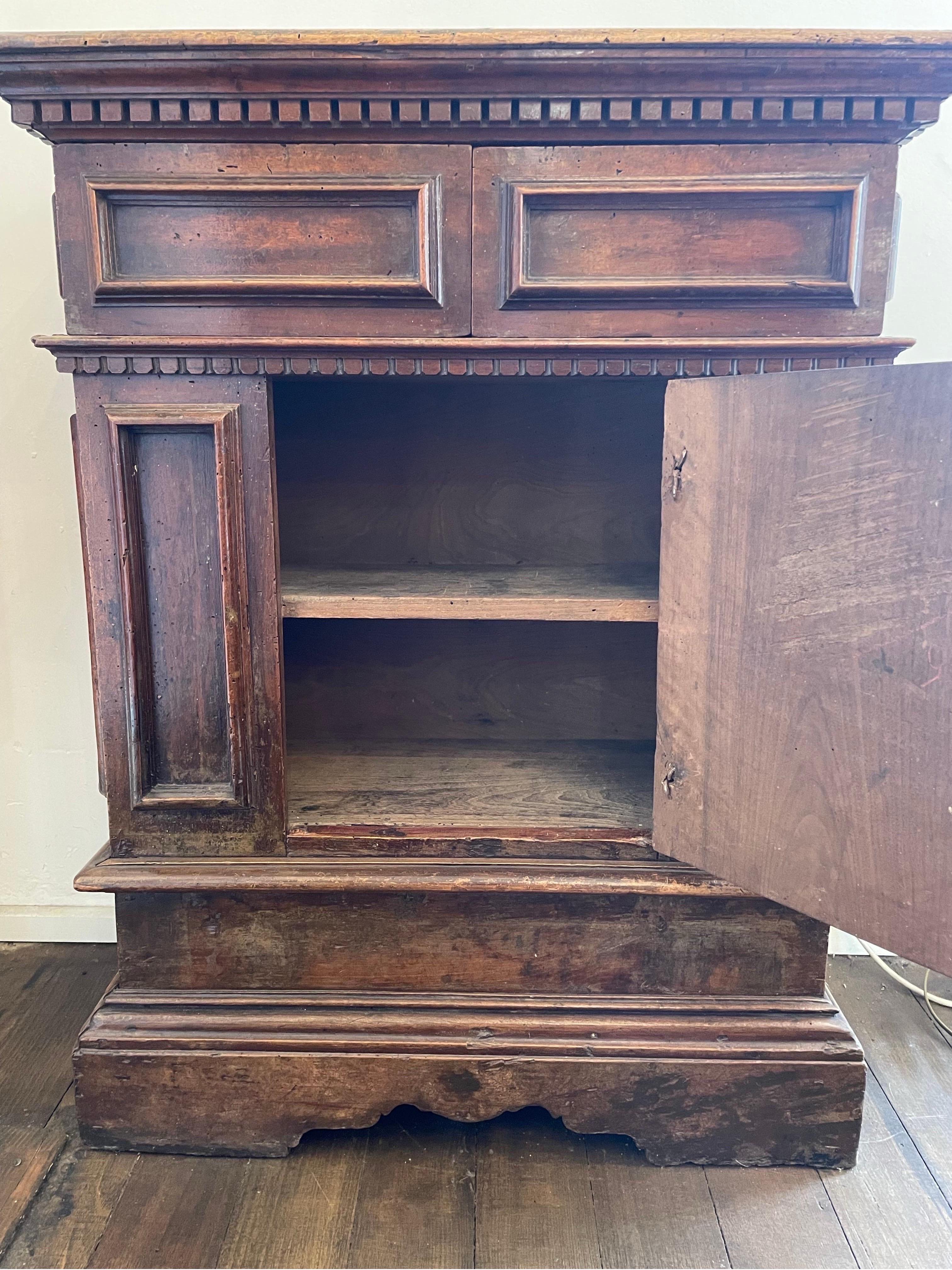 Description: 

A rectangular credenza or dining room sideboard. The rectangular top with a dentil cornice above a horizontal panelled section with two concealed frieze drawers to the front, beneath which is a smaller secondary shaped dentil cornice