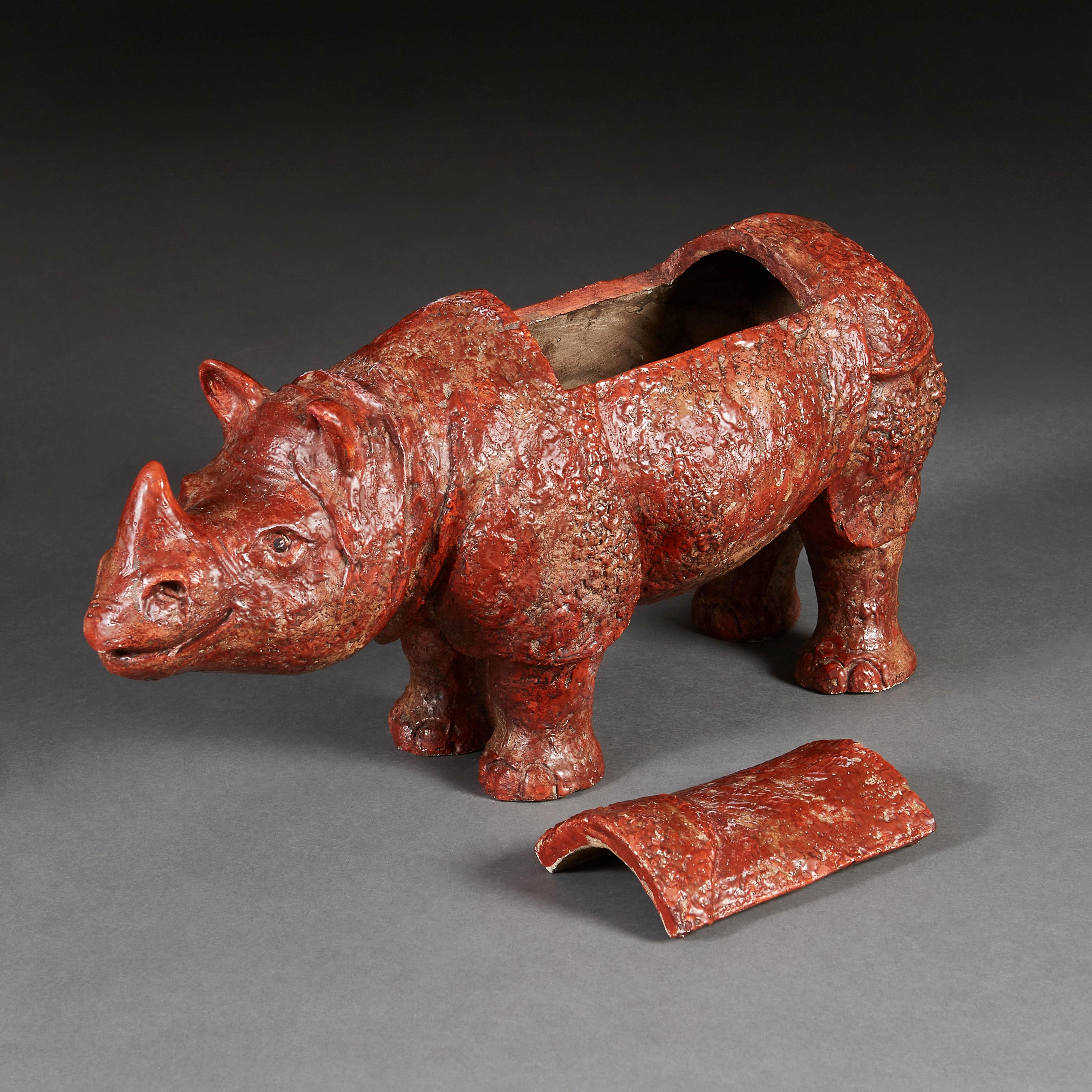 An unusual early twentieth century ceramic sculpture of a contented rhinoceros, with red glaze, the top section opening to reveal a cavity.
 
  