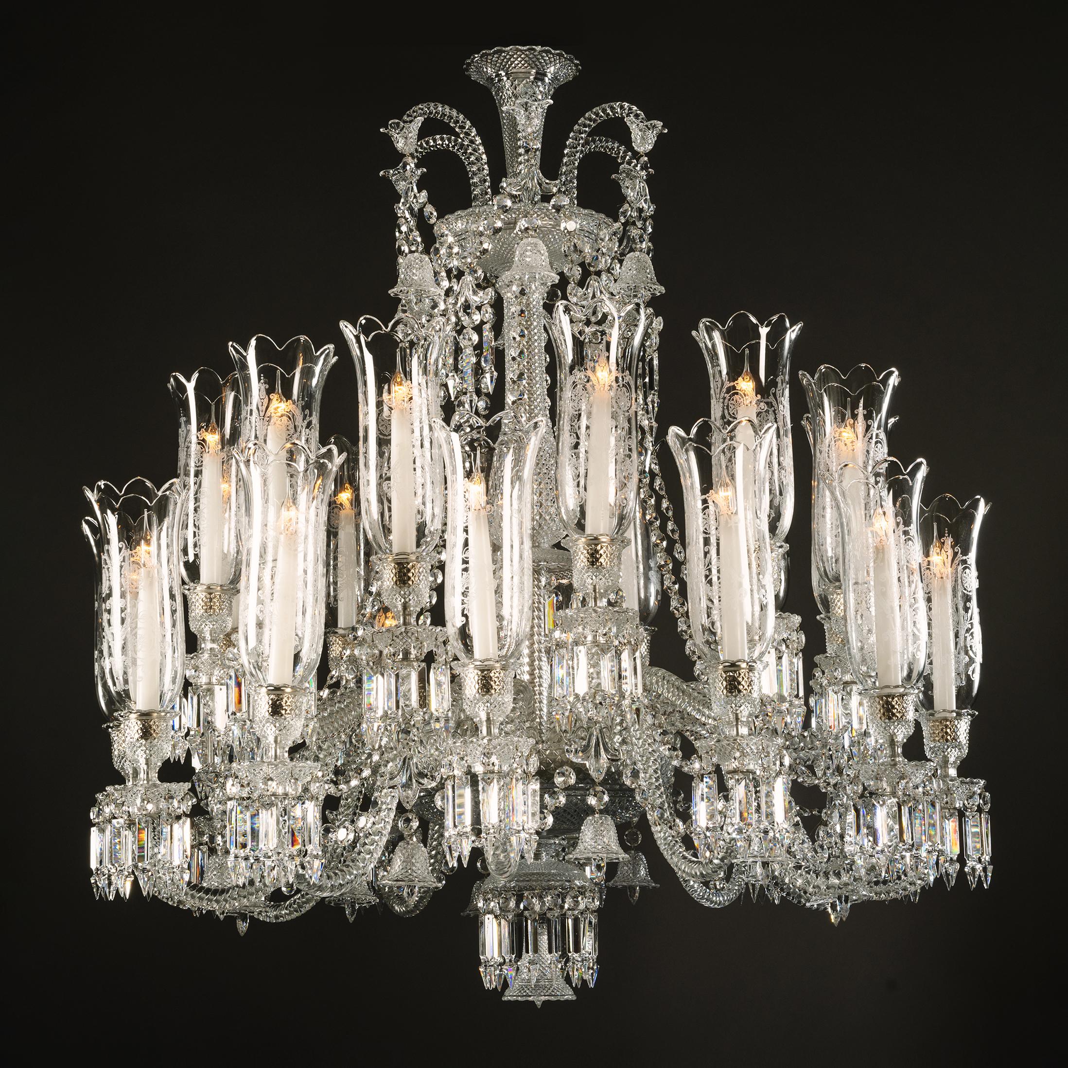 A Twenty-Four Light Crystal Glass Chandelier, By La Compagnie des Cristalleries de Baccarat.

The trumpet-shaped corona issuing cane-shaped branches hung with tulip bells. Above a hobnail cut upper stem and pendant hung canopy. Issuing S-scrolled