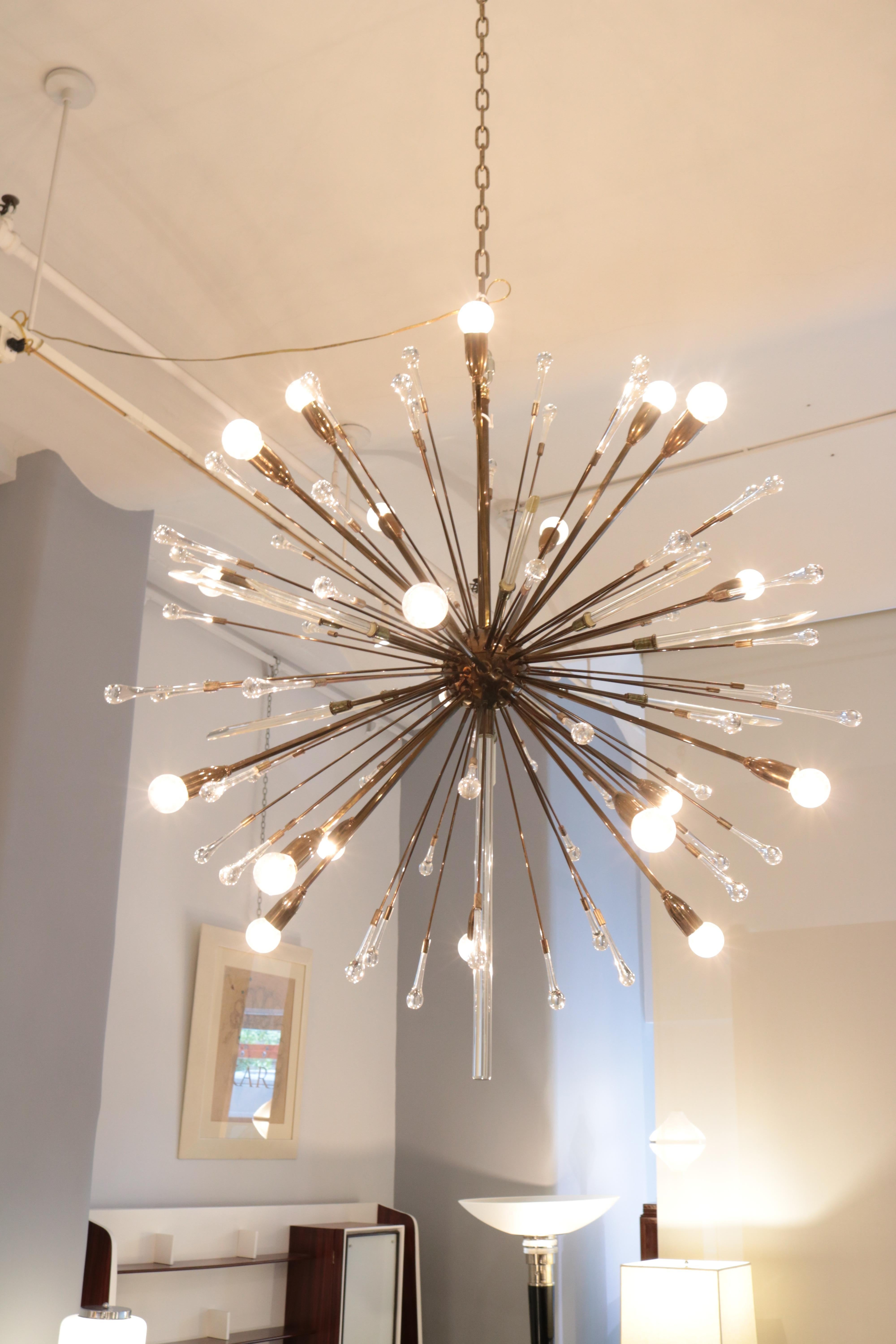 A 20 light Modernist Sputnik chandelier. Patinated brass with brass rods 
extending out from the center in all directions. The rods end with lightbulb sockets , 
crystal teardrops or cut crystal shafts.