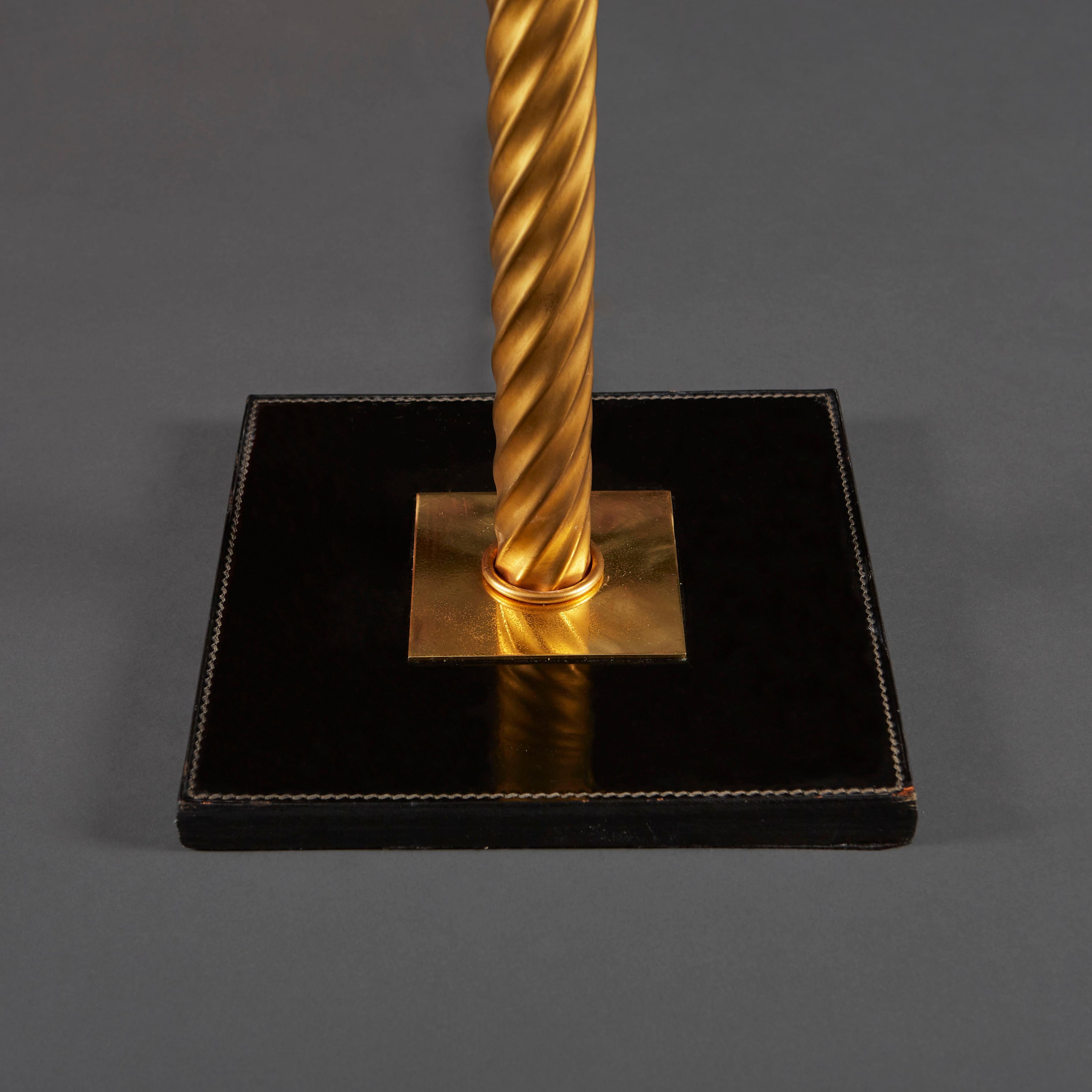 Une inhabituelle lampe à colonne en laiton torsadé montée sur une base carrée en cuir noir, d'après Jacques Adnet.

Veuillez noter que l'abat-jour n'est pas inclus. 

Actuellement câblé pour le Royaume-Uni.