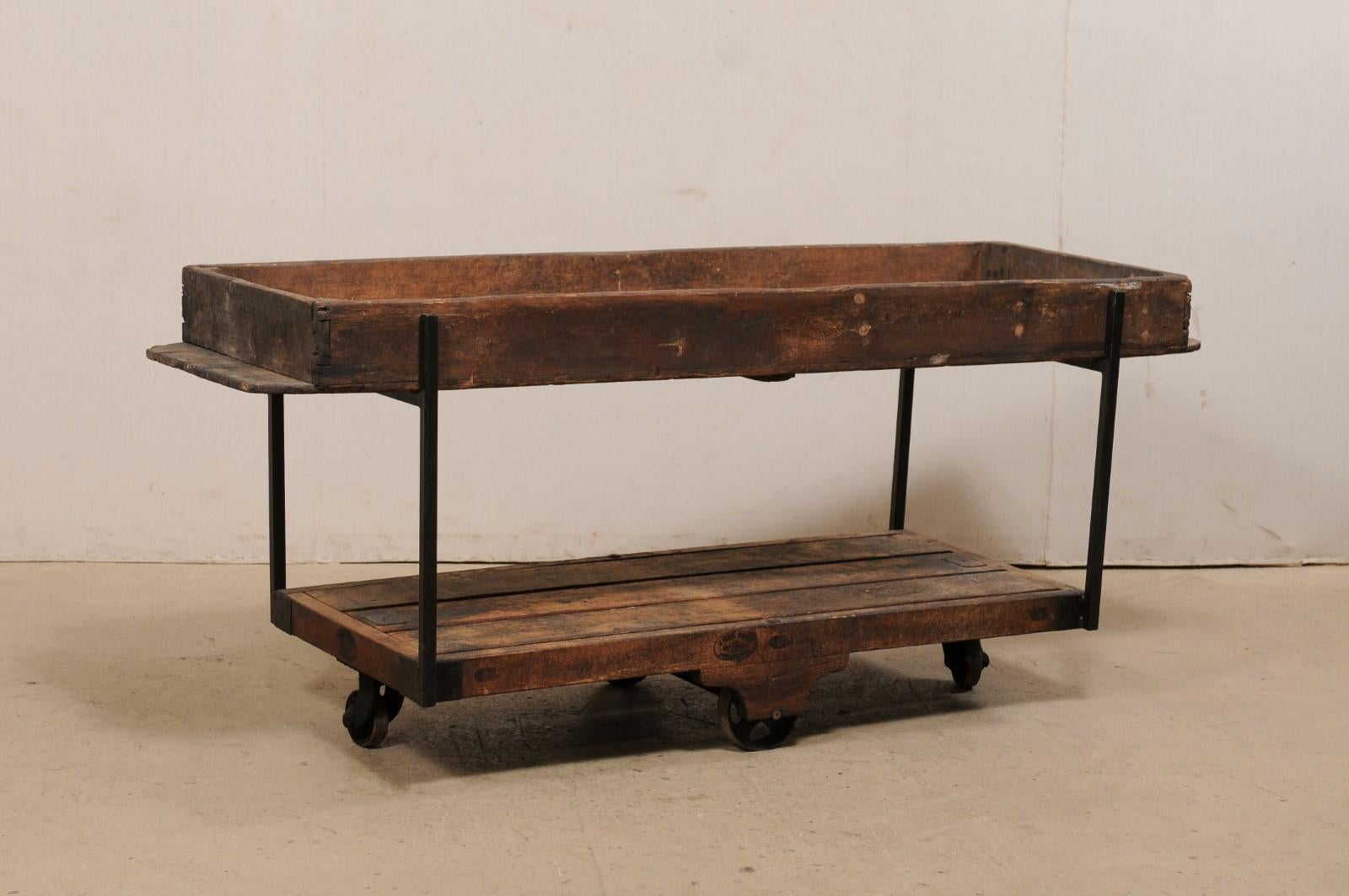 A custom created two-tiered table from 19th century Spanish baker's bread risings shelves. This 6.75 foot long table features an overall rectangular-shape, fashioned from two wooden Spanish bakery shelves, used in the rising of bread loaves. The