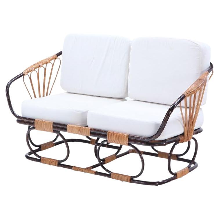A two-tone French rattan settee with cushions. Circa 1970