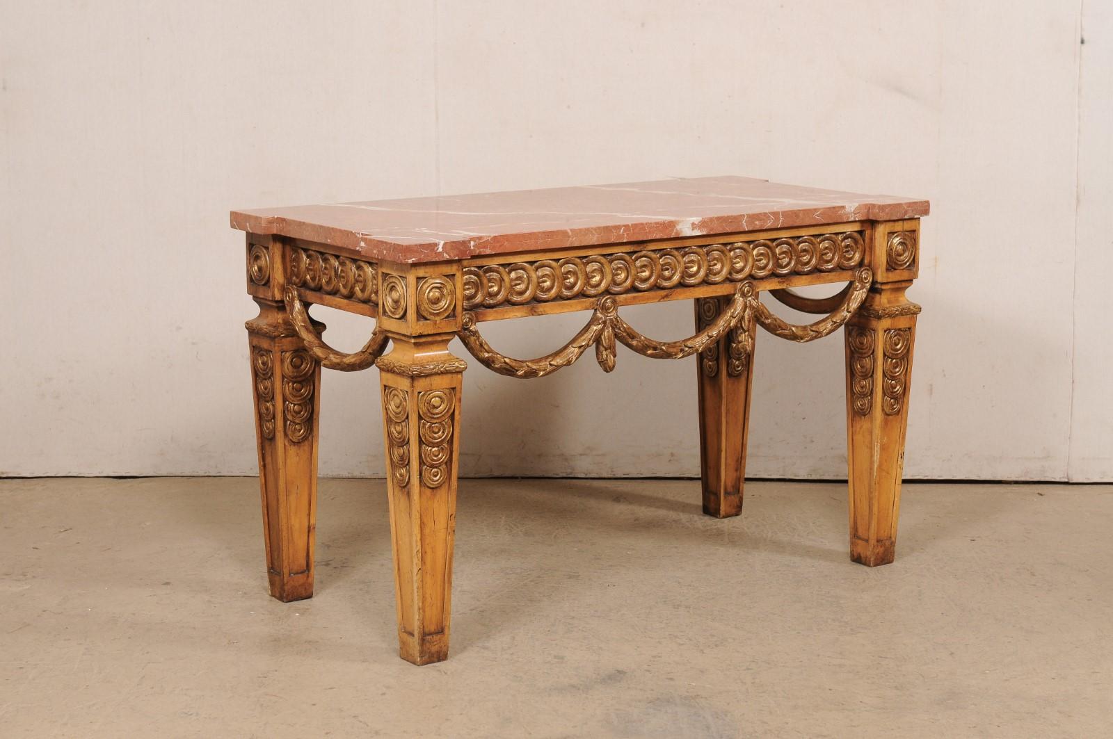 A large-scale American carved-wood console with marble top and garland swagged skirt. This vintage table made in America, features a rectangular-shaped marble top (with corners emphasized and squared outwardly), atop an apron adorn with overlapping