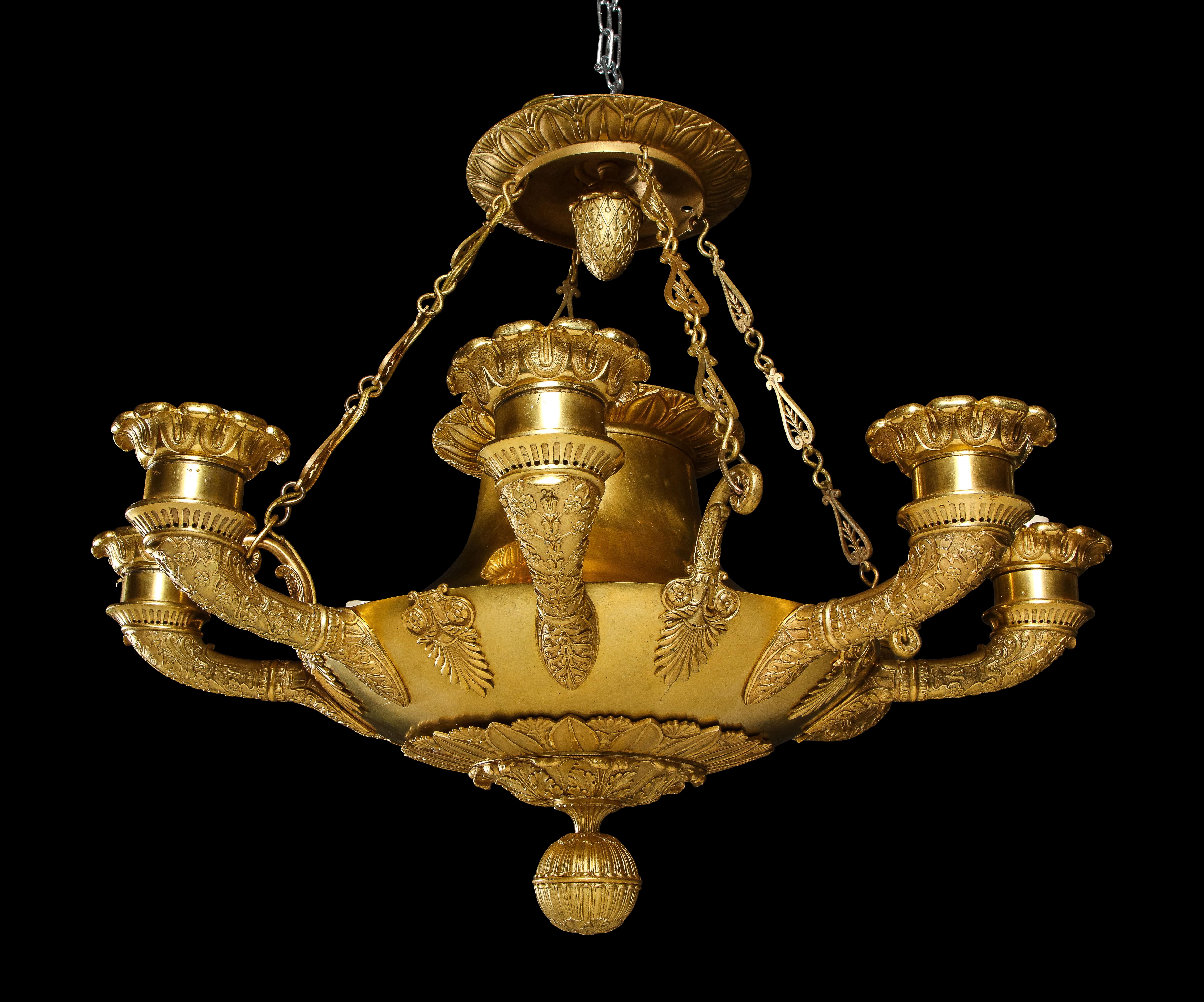 Questo insolito lampadario Antique French Empire in bronzo dorato incarna l'estetica raffinata dello stile neoclassico. Presenta molteplici bracci graziosamente curvi, ciascuno delicatamente ornato da catene reticolate in bronzo dorato che scendono