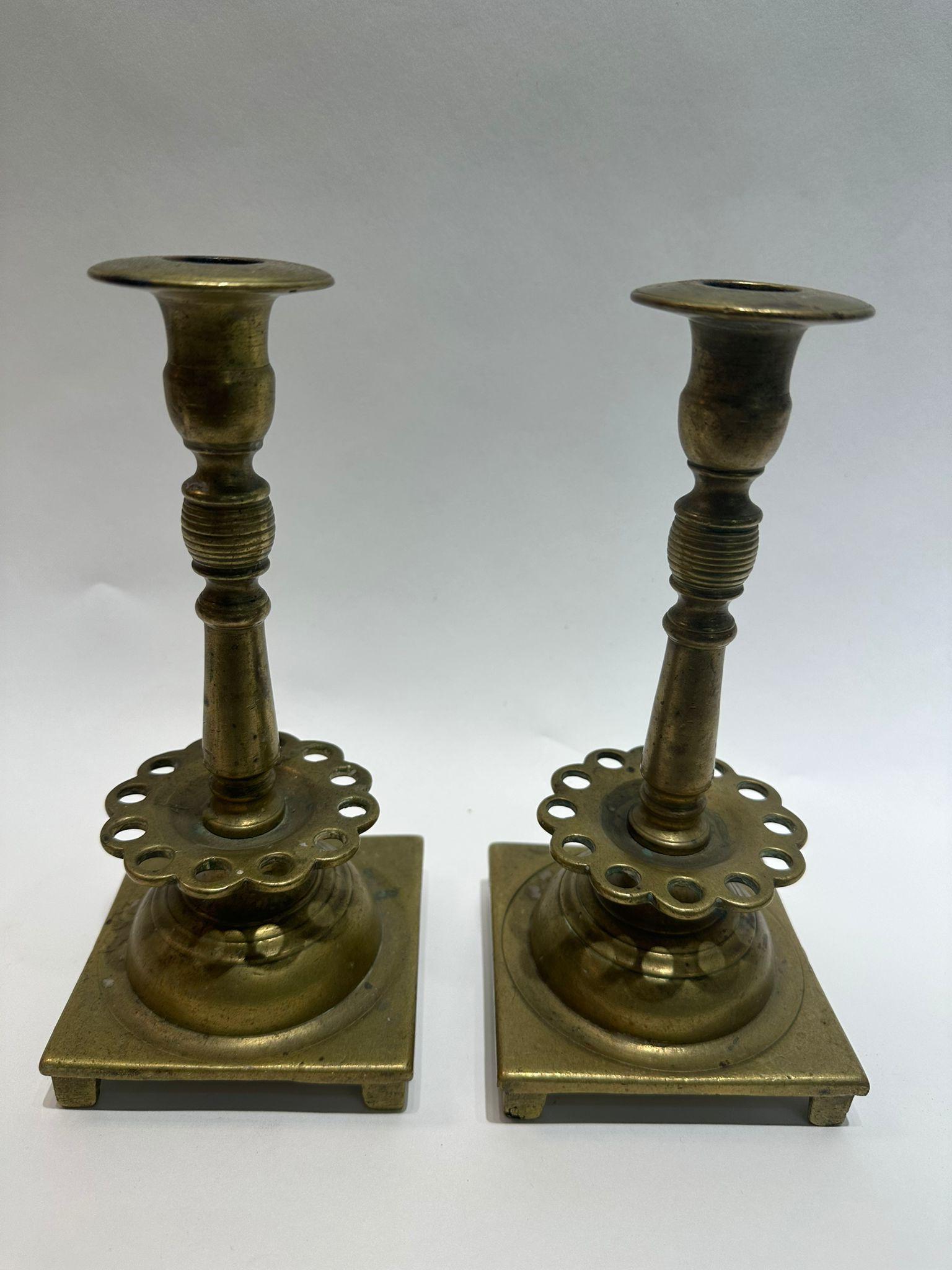 This pair of primitive 18th-century Polish brass candle holders originates from the Jewish shtetls of Eastern Europe, where they were used for Sabbath and holiday observances. Crafted with a practical three-part design, they can be easily dismantled
